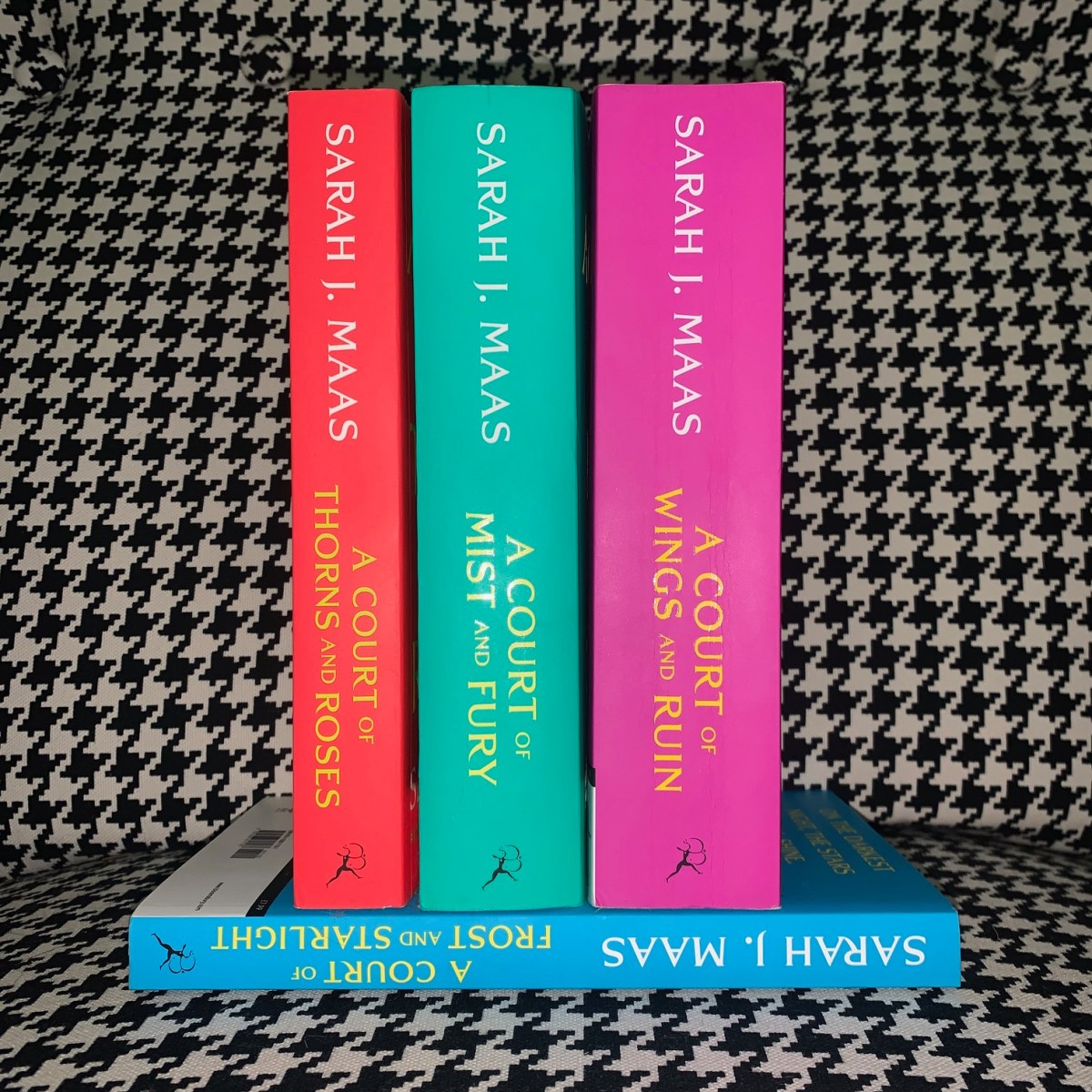 The four books in the A Court of Thorns and Roses series with a black checkered background.