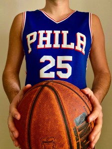 A basketball player holding a basketball. The players jersey reads PHILA 25.