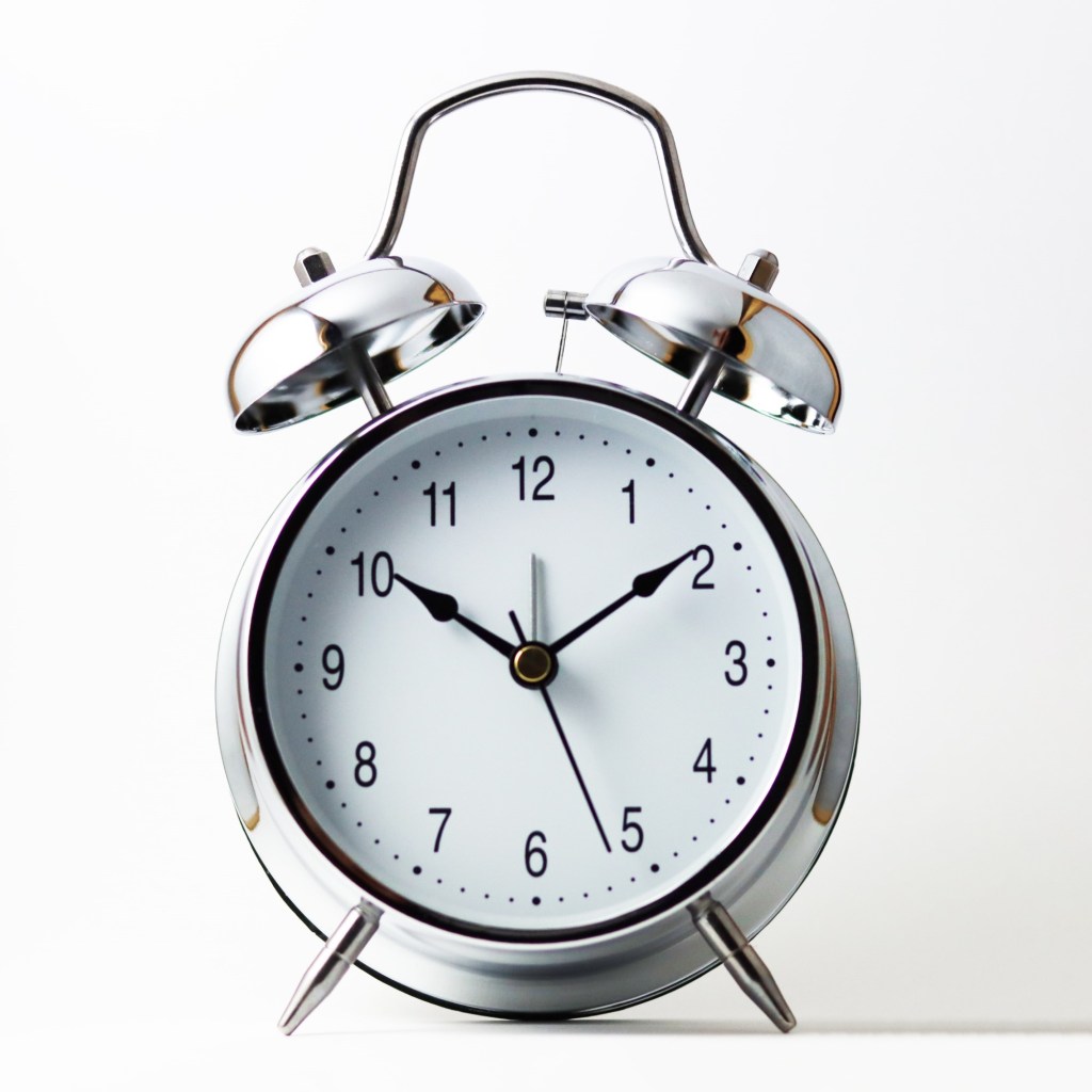 A silver alarm clock against a white background