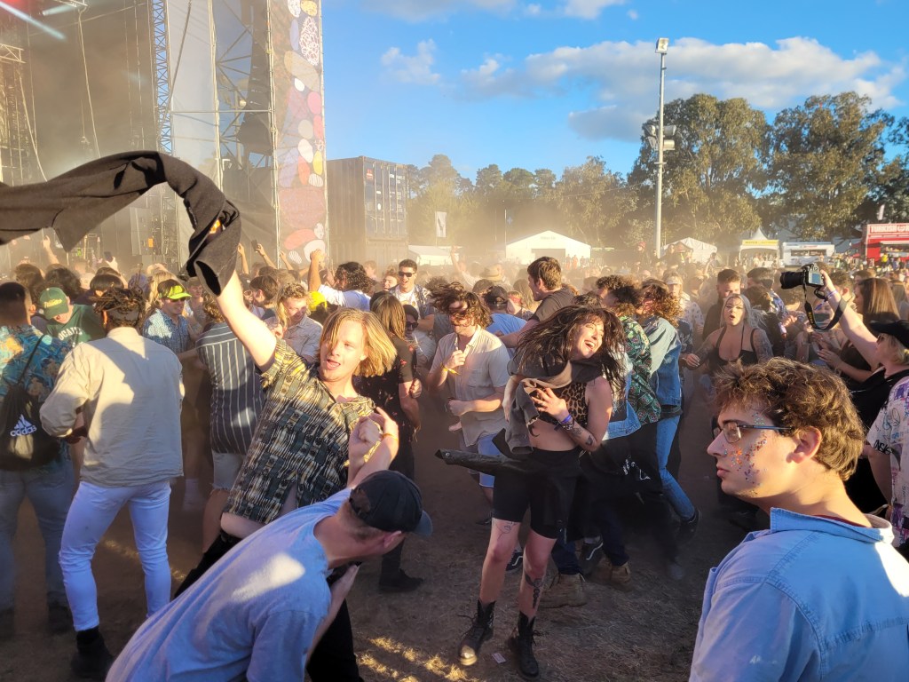 Happy people in a mosh pit, one man is swinging his short in the air.