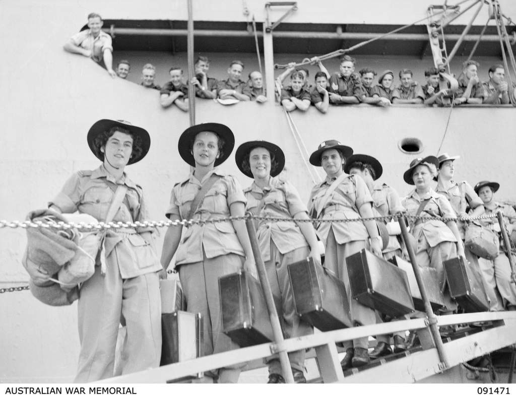 Australian Women's Army Service (AWAS) personnel moving down the gangway to the waiting landing barges during disembarkation from the MV Duntroon. The Duntroon carried a group of 342 AWAS from Australia to Lae who are going to the AWAS barracks at Butibum Road. Identified personnel are: (left to right) Private L L Gospel; Pte J I Peters; Pte M K Cameron; Pte B C Moat; unknown (partially obscured); Pte D Bannister; Pte M J Chalkley; Pte D H Robson.