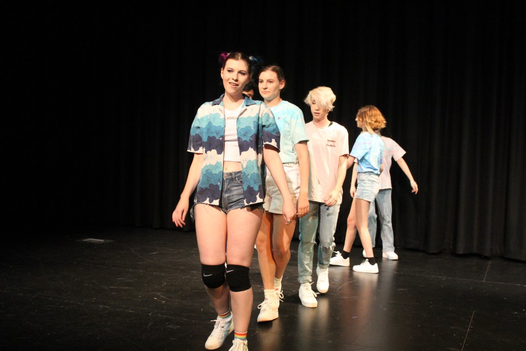 5 dancers standing in a line wearing pastels and blues