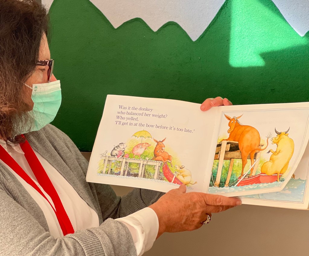 Teacher reading a picture book while wearing a mask.