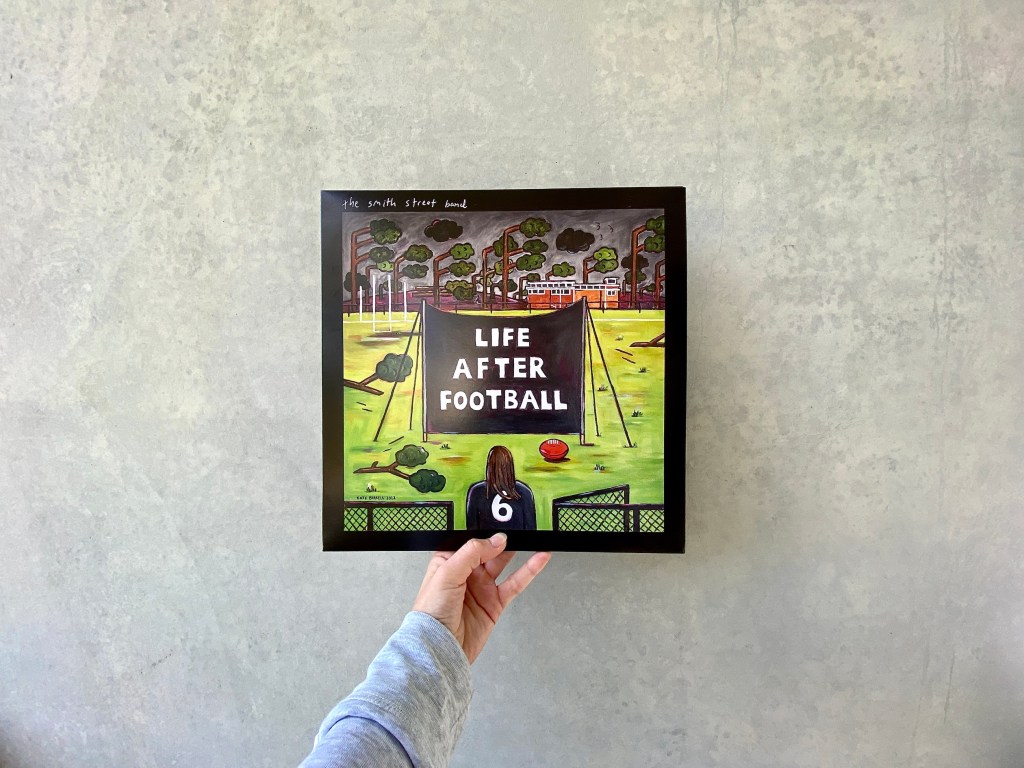 Life After Football record cover, held up in front of concrete wall