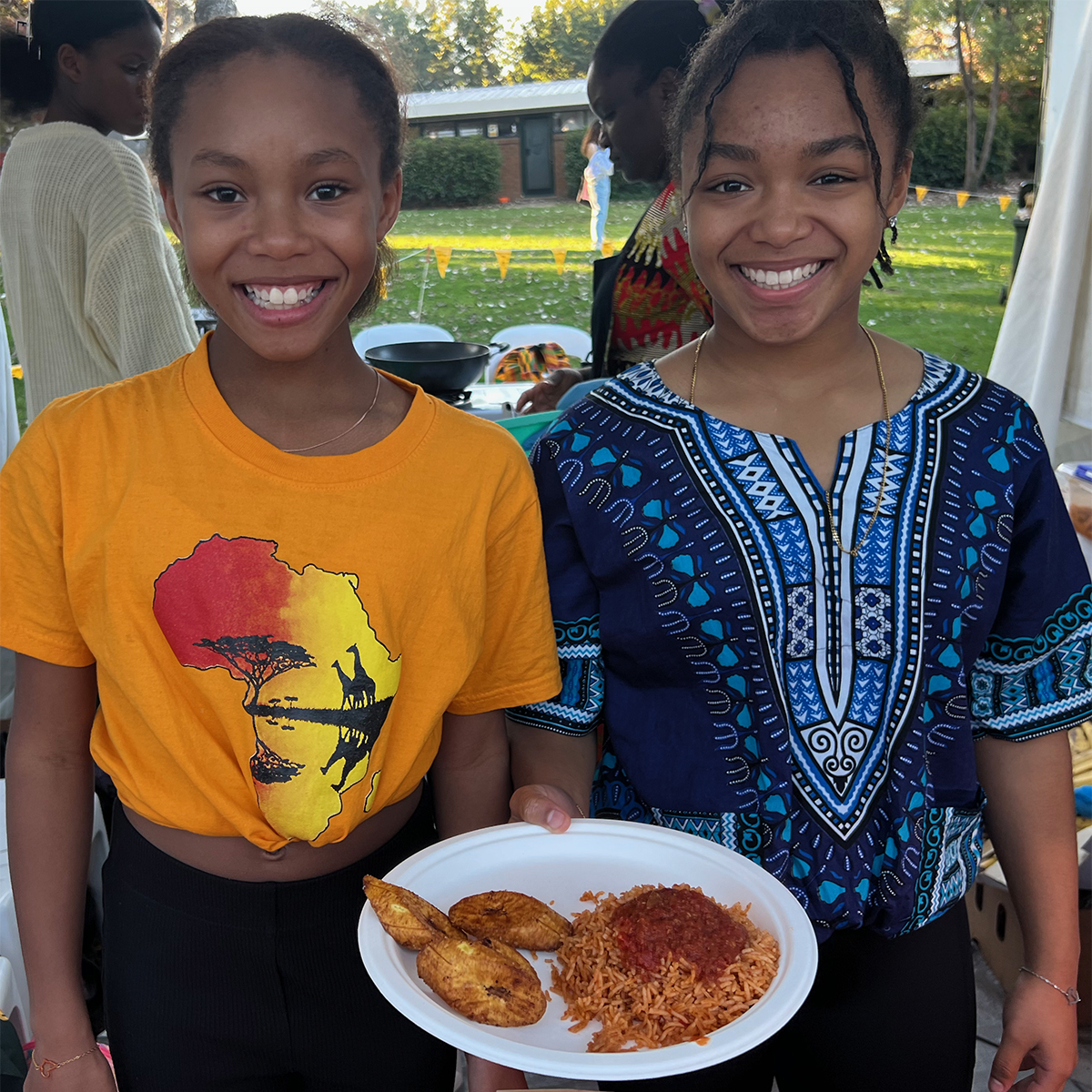 Two young girls serving jollof from Ghana