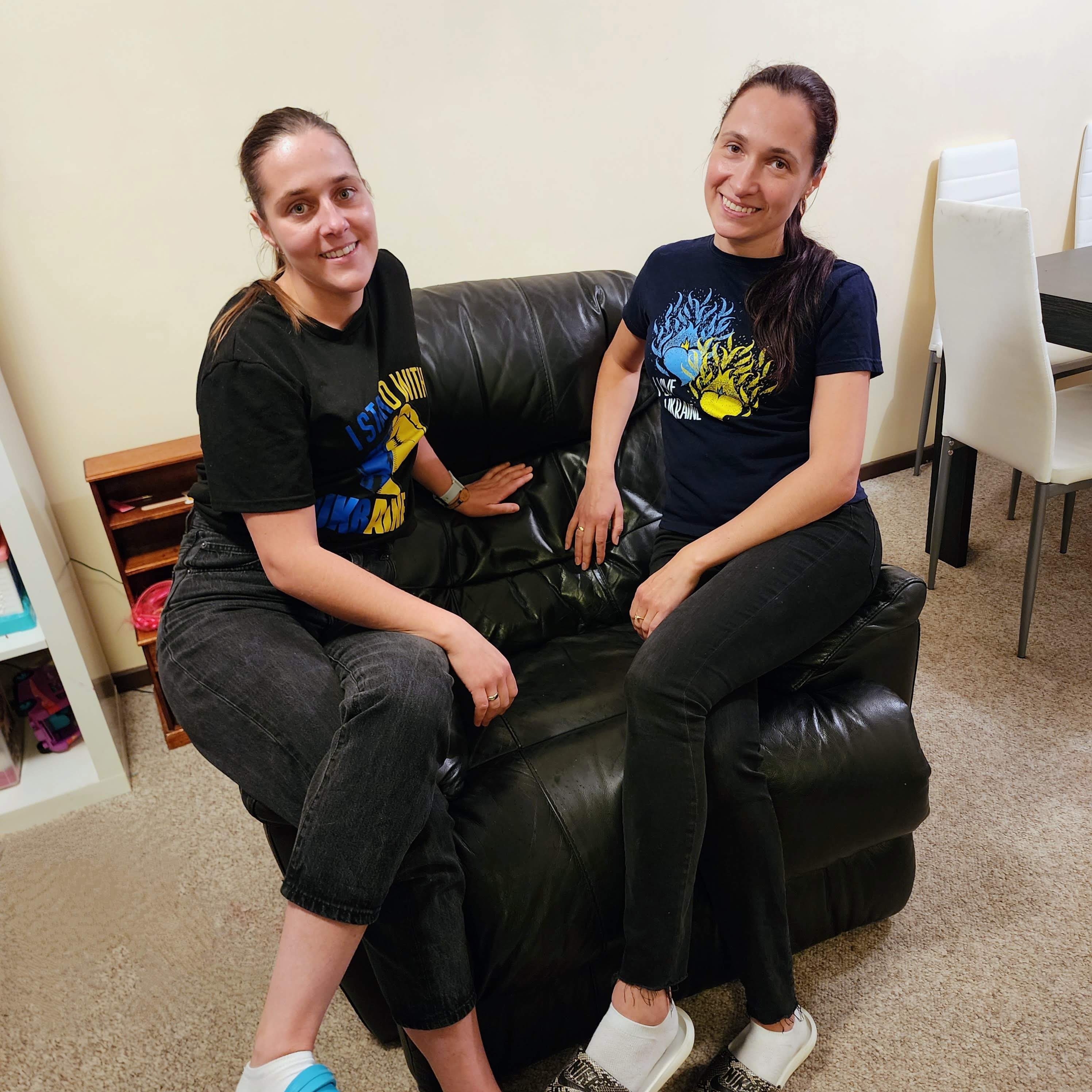 Yustyna and Yaryna siting on their couch and smiling