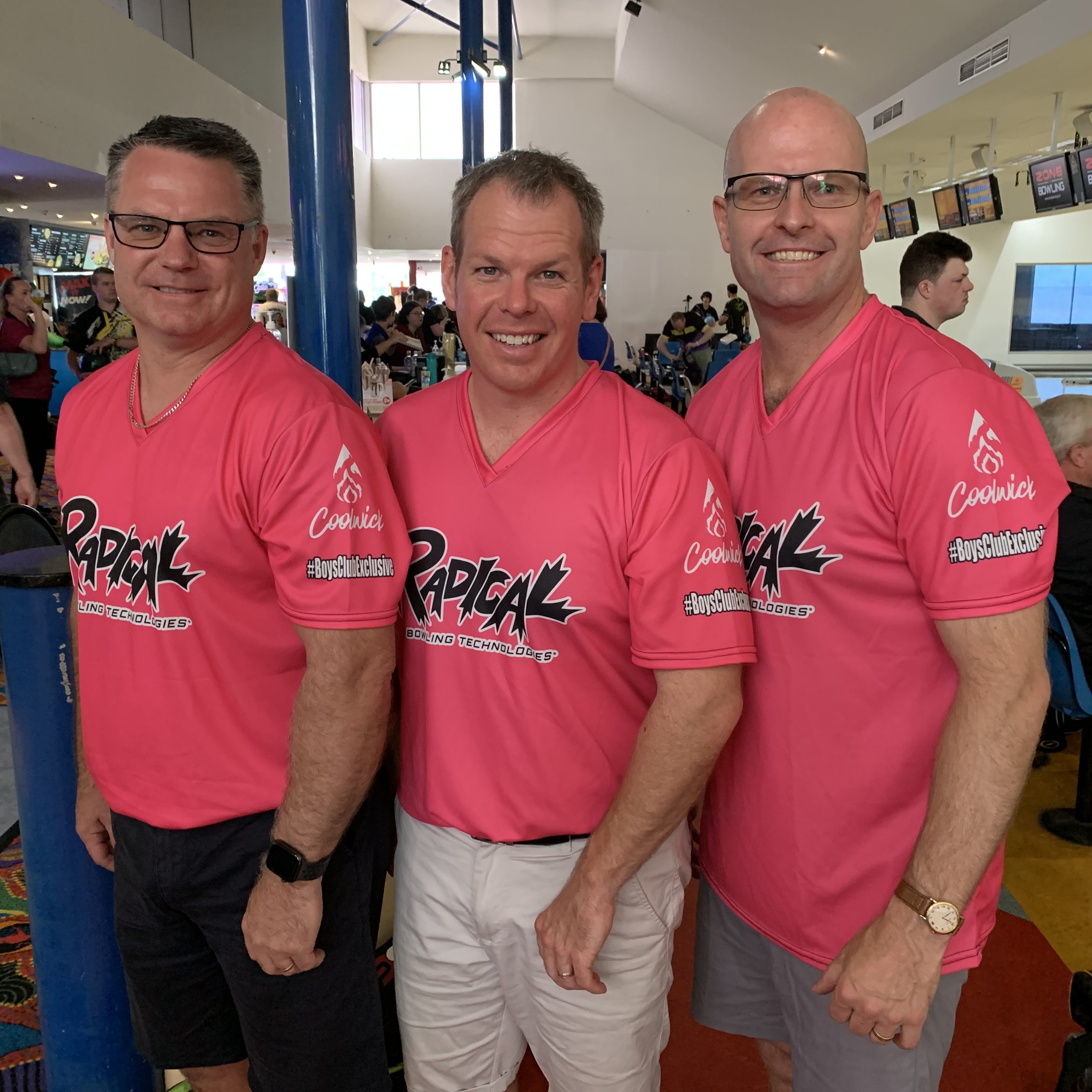 3 men in pink shirts smiling