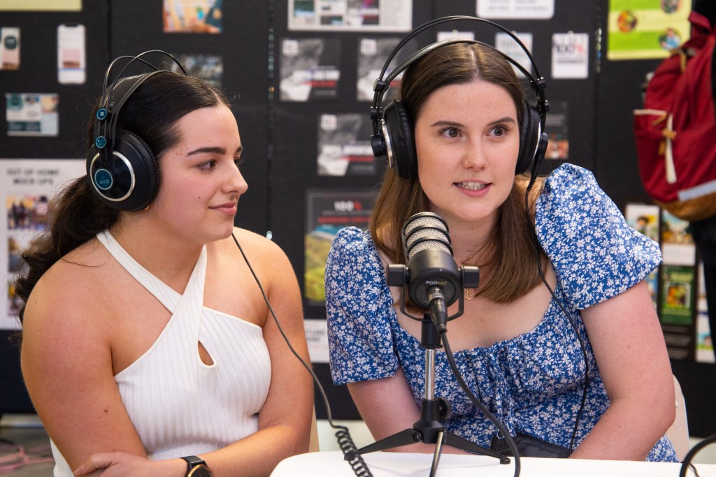 Two Communications and Media students being interviewed, wearing headphones