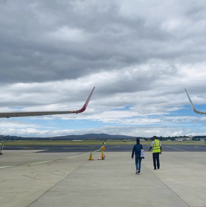 woman on tarmac with baggage handler approaching plane