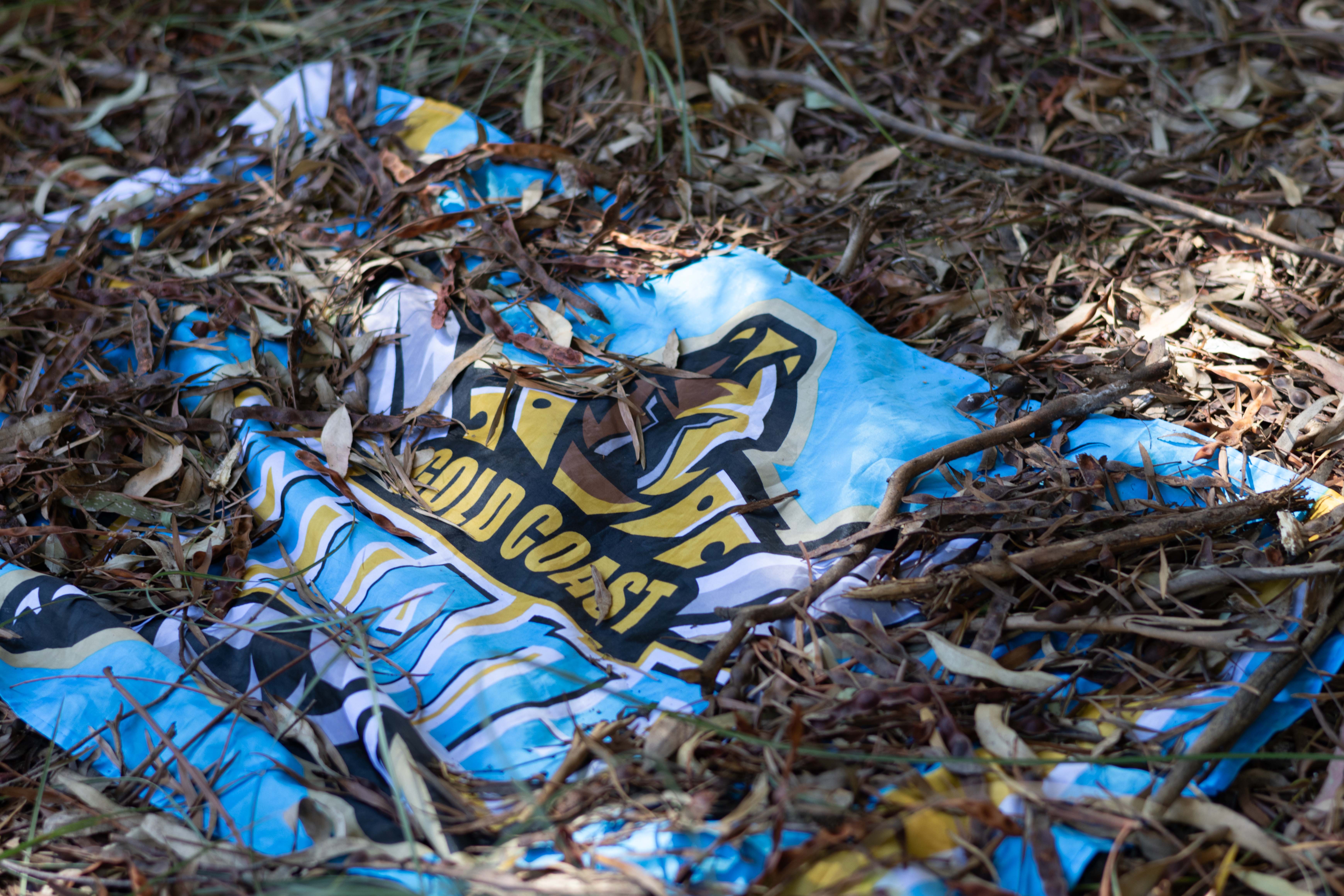 Gold Coast Titans flag half buried in the dirt.