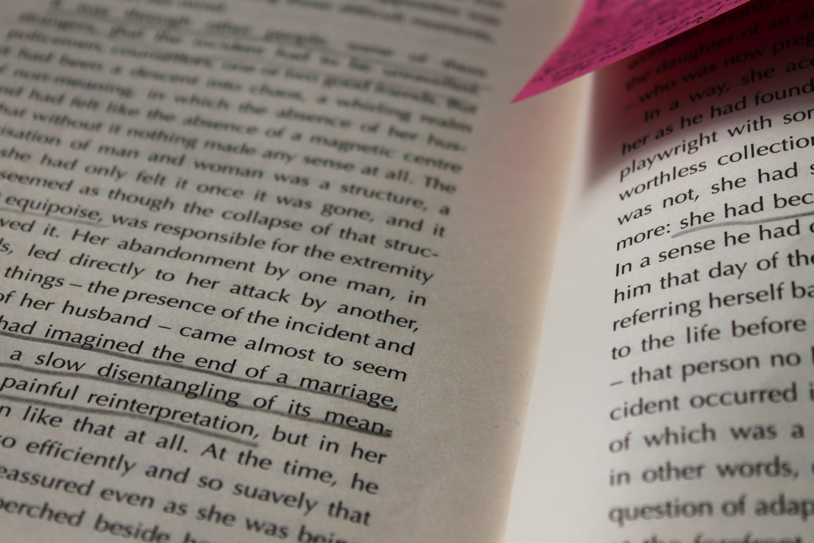 Black text inside a book with a pink sticky note