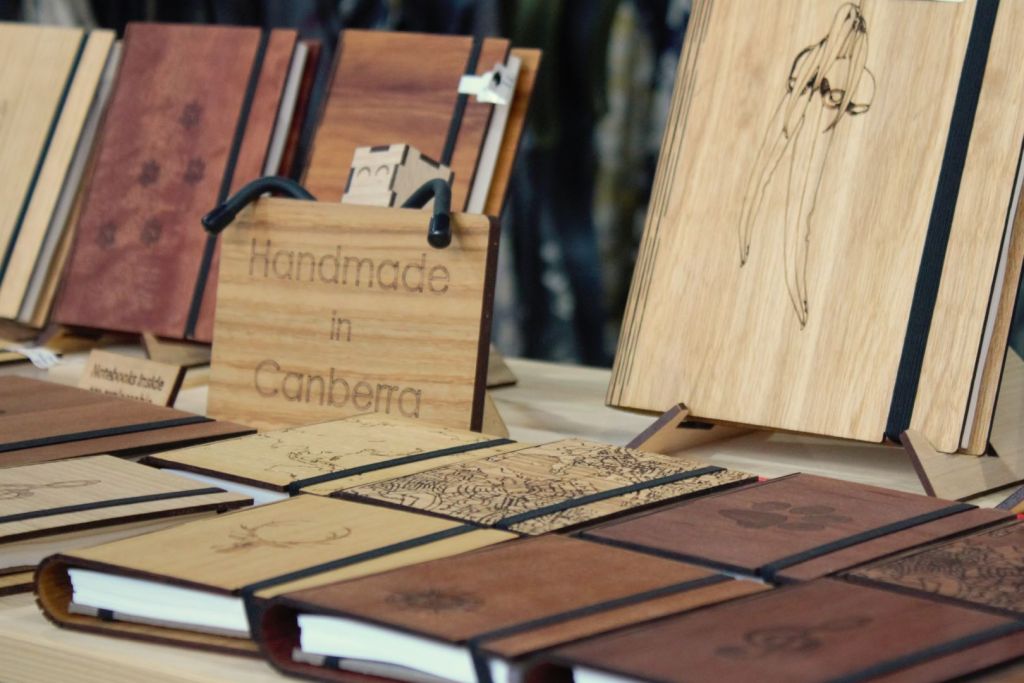 Plywood journal covers next to a wooden sign which says "Handmade in Canberra"