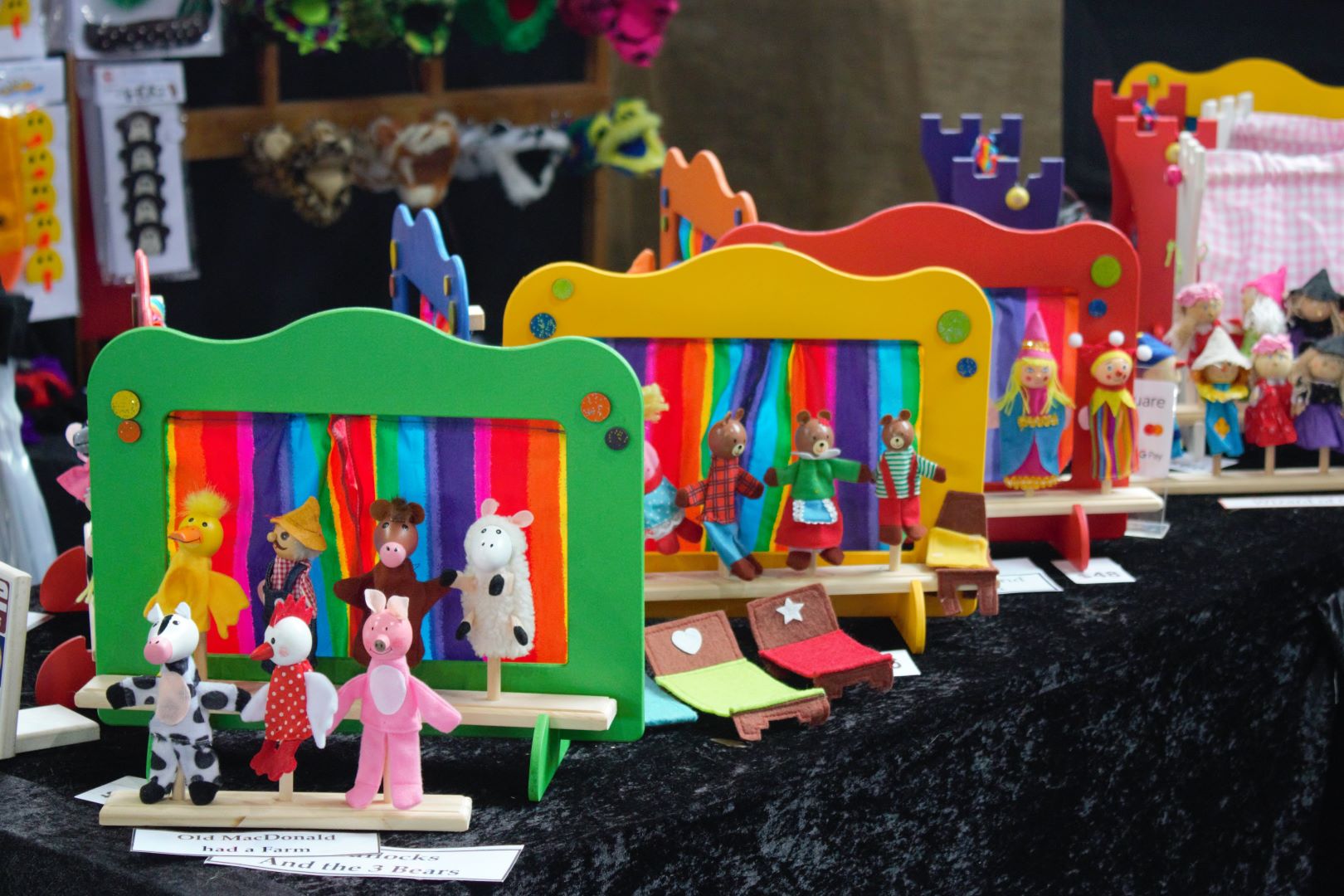 Colourful hand puppets on display in front of hand-made wooden puppet theatres