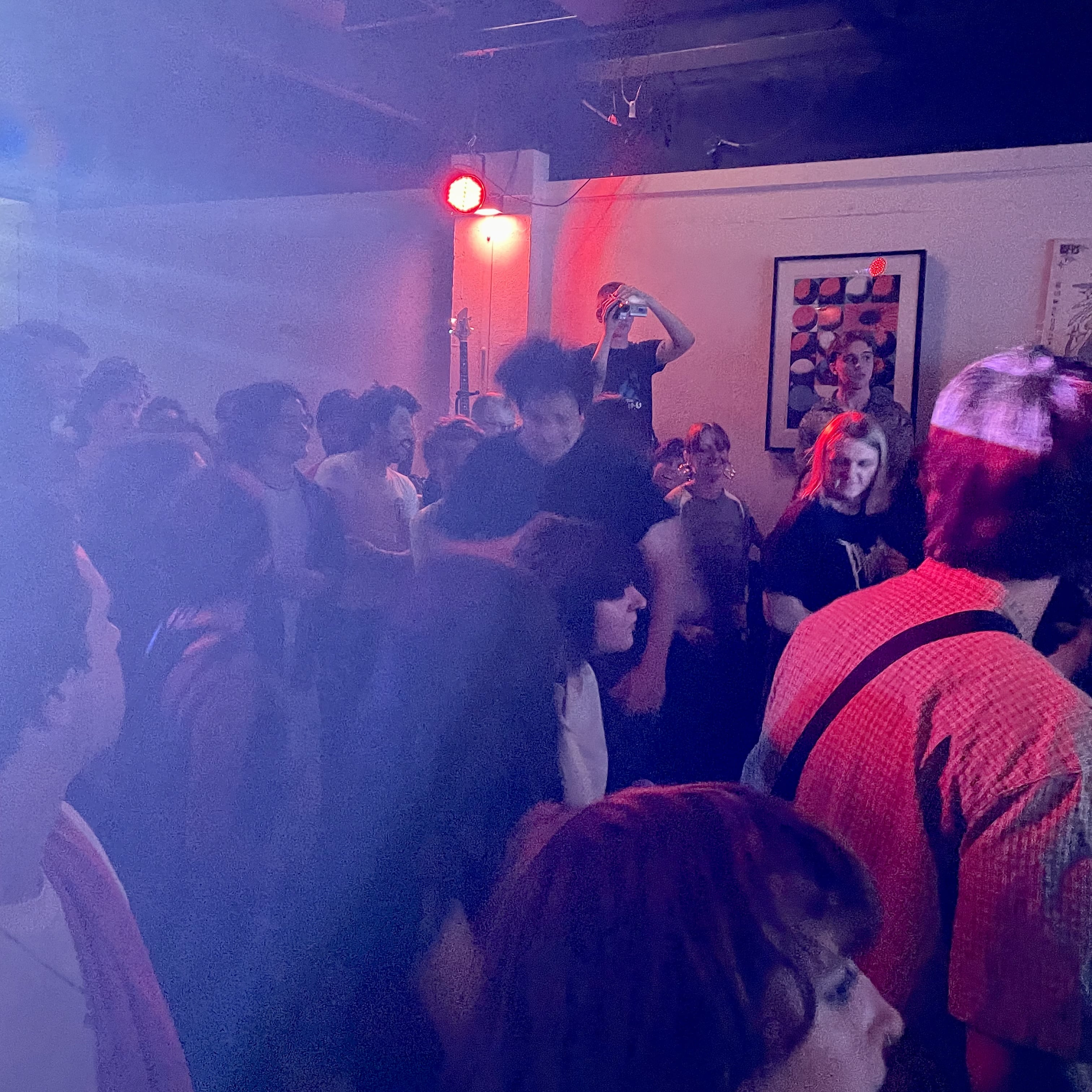 A crowd of people watching the band play. A mosh pit is beginning.