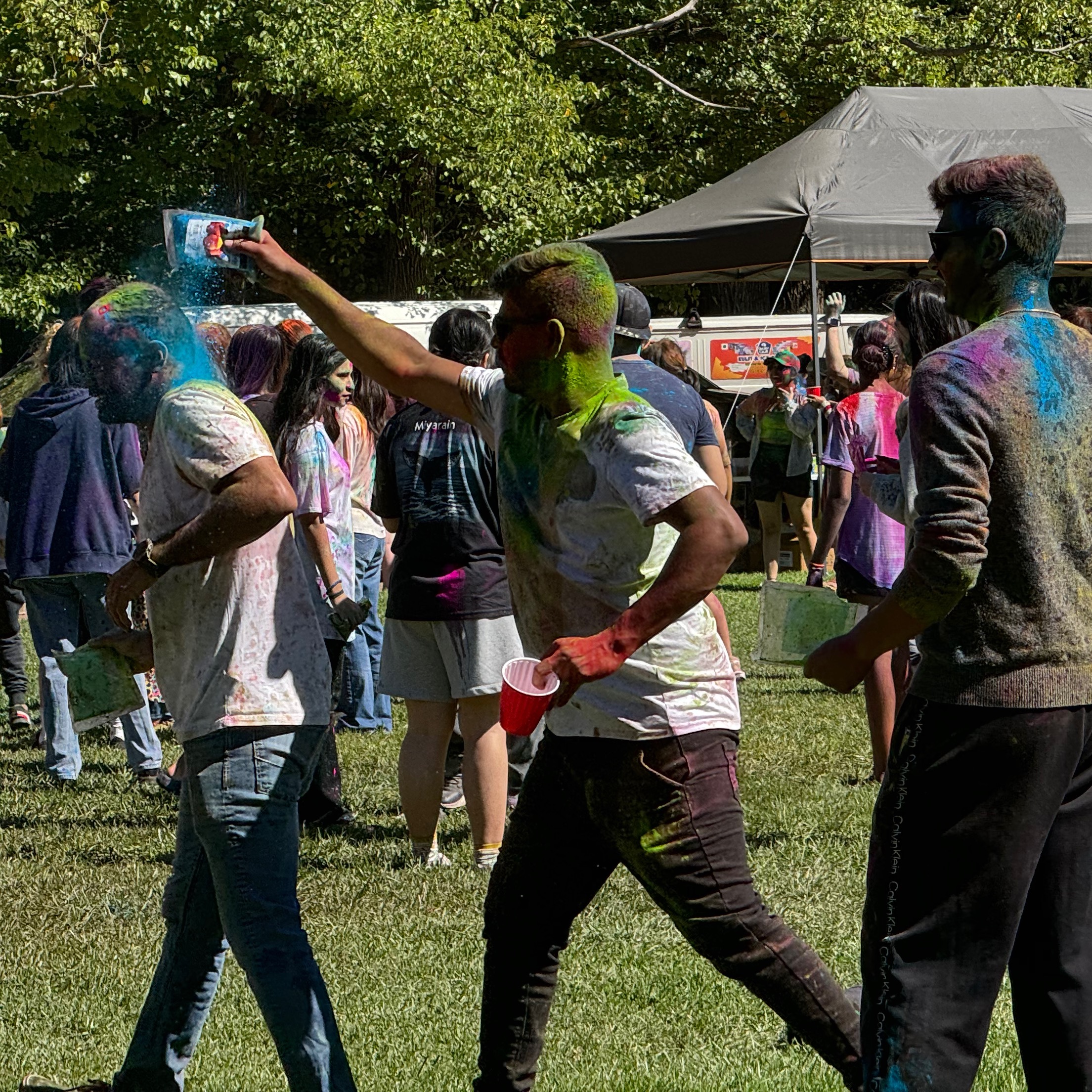 man putting blue powder on another man while another man watches. 