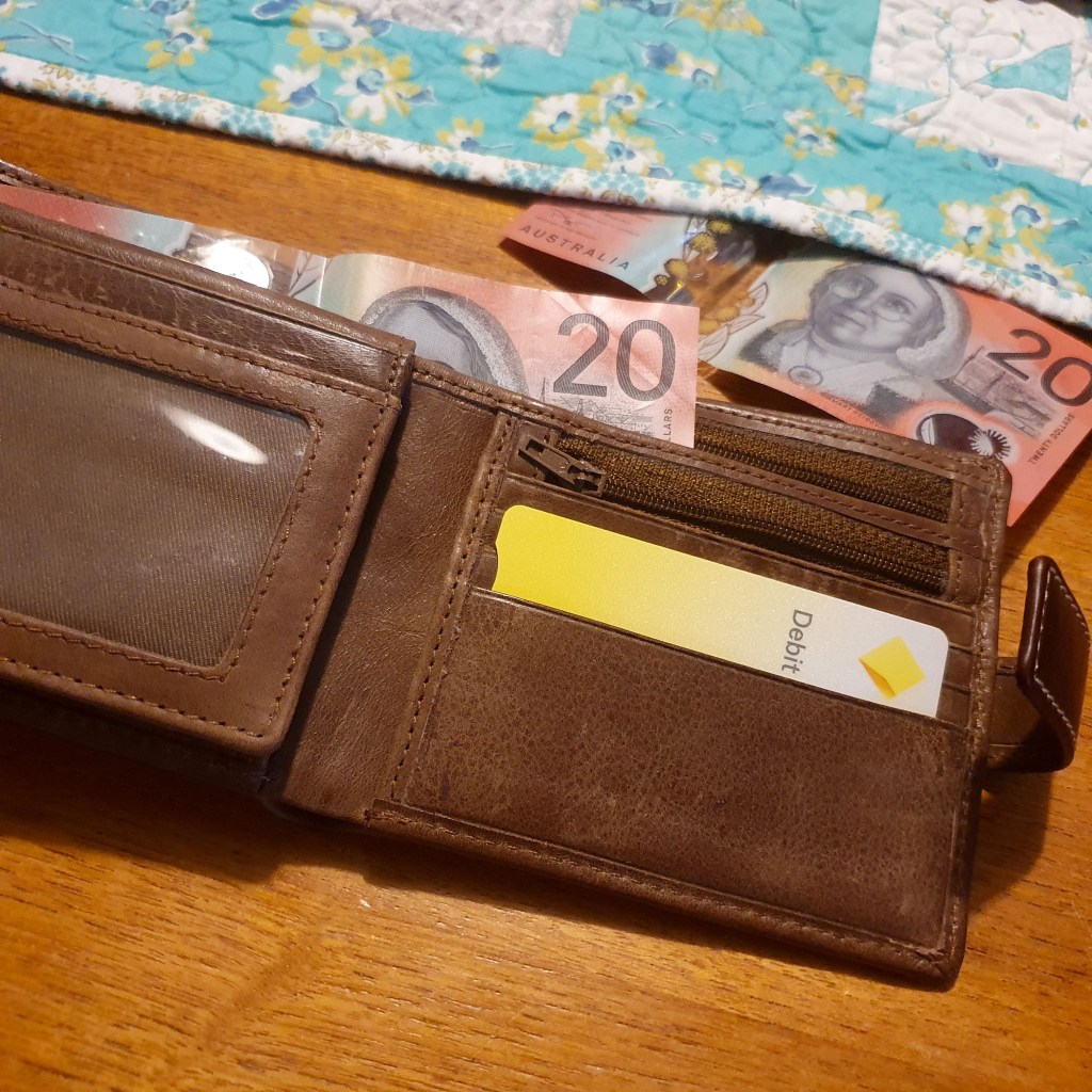 Brown wallet with notes and debit card.