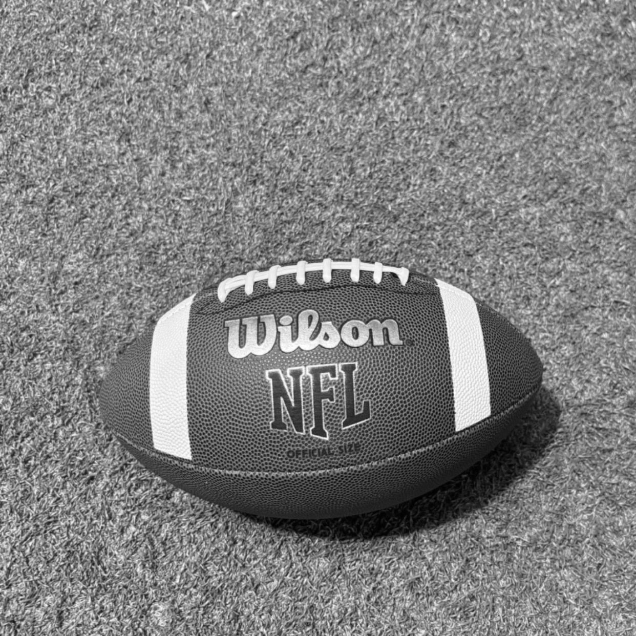 black and white image of NFL ball on fake grass background