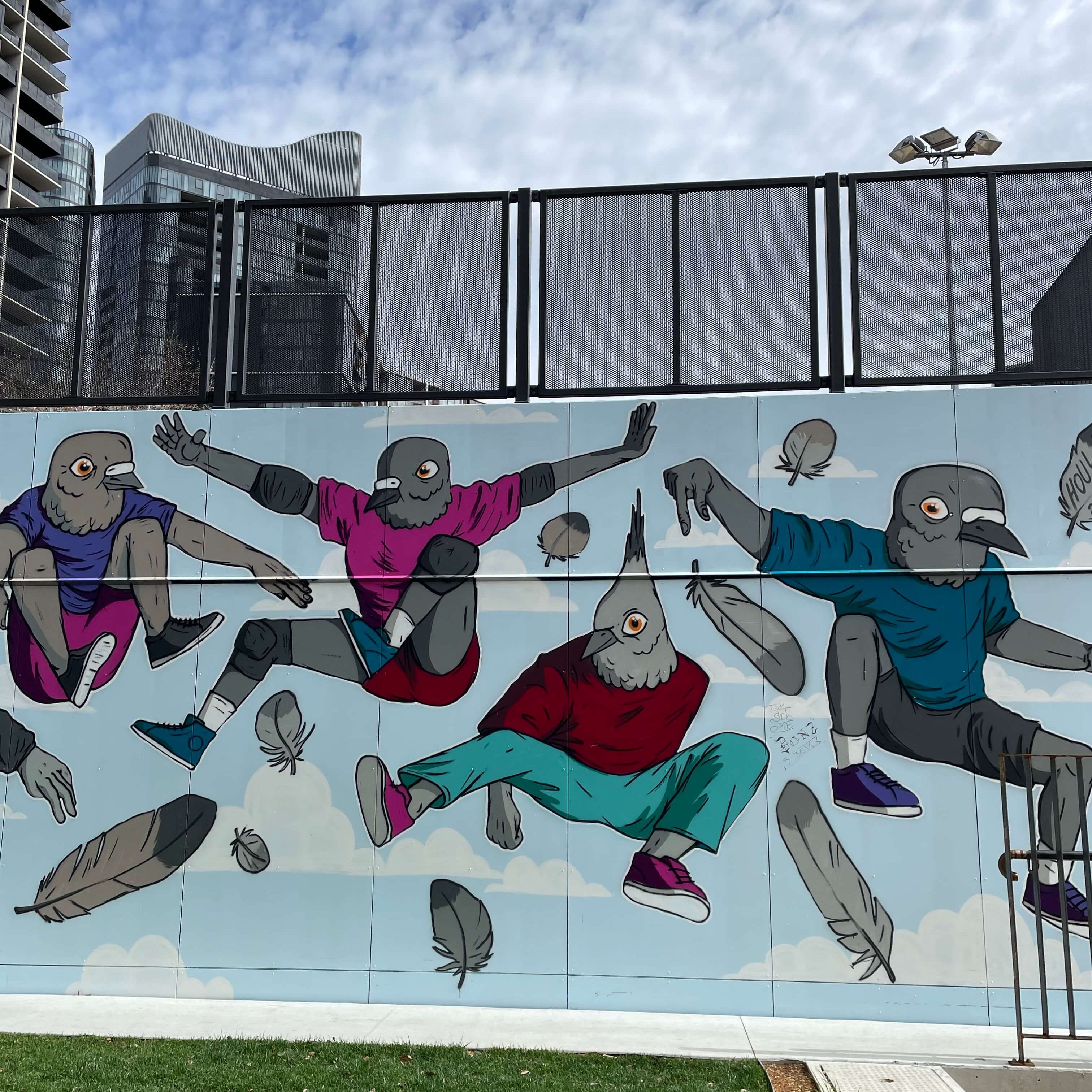 A mural on the Belco vert ramp. The artwork features people with the head of a pigeon. From left to right, each figure is jumping and doing a skateboard trick.