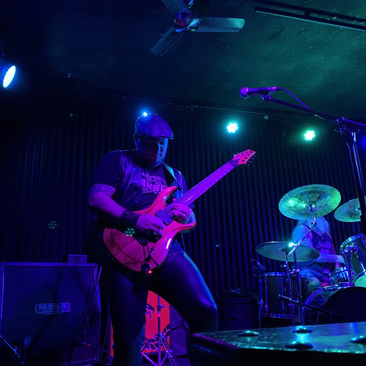 Man with guitar plays on stage with blue and purple lights