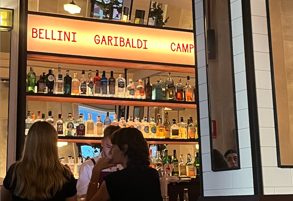 Fully stocked bar with women sitting in front of it