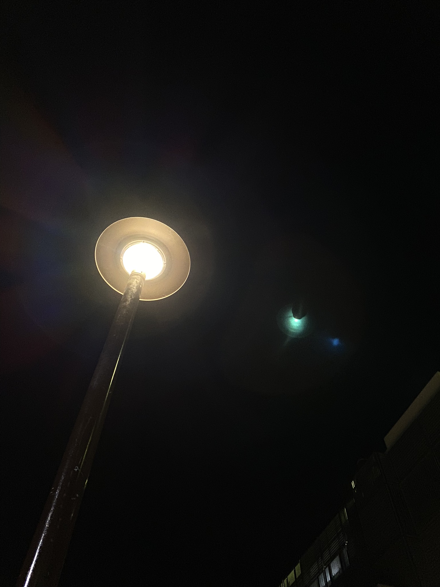 An upward angled photo of a top-covered street light in Canberra's CBD, the night sky in the background is pitch black with no visible stars.