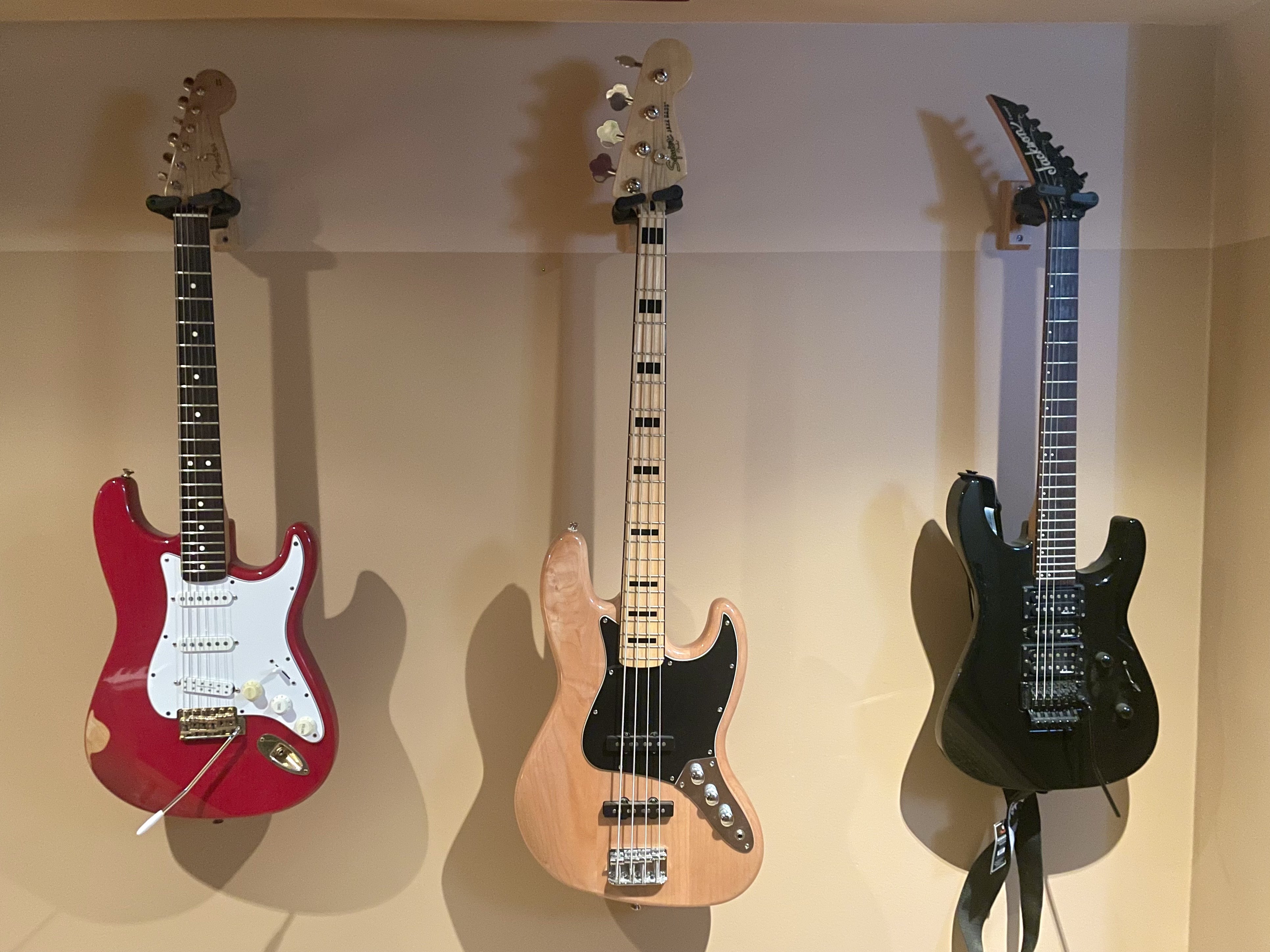 3 electric guitars hanging on a wall