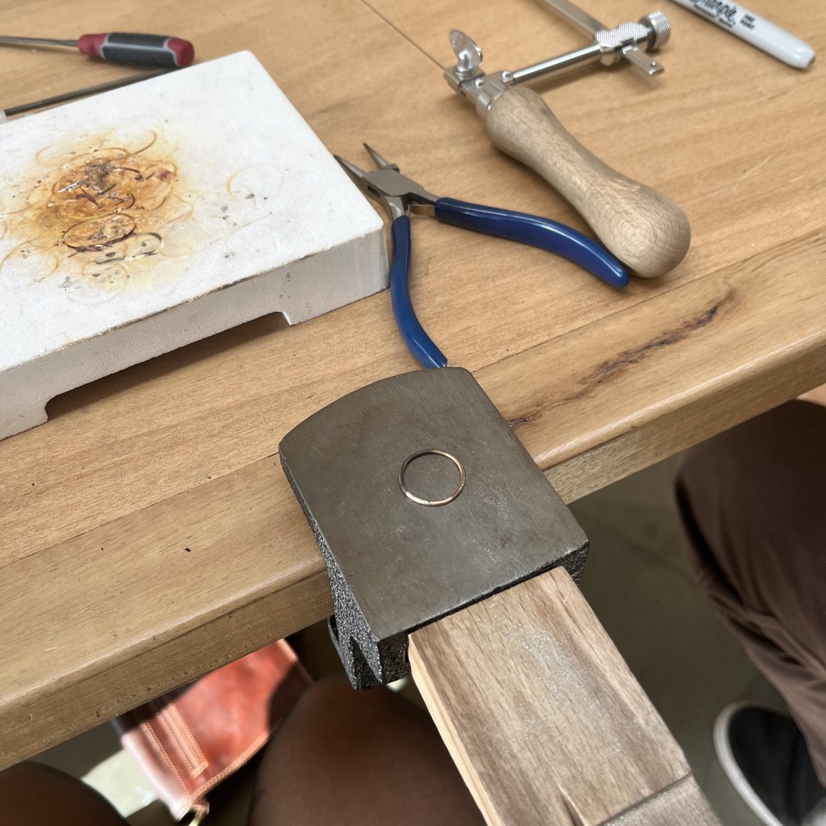 Completed handmade ring sitting on workbench with tools surrounding it
