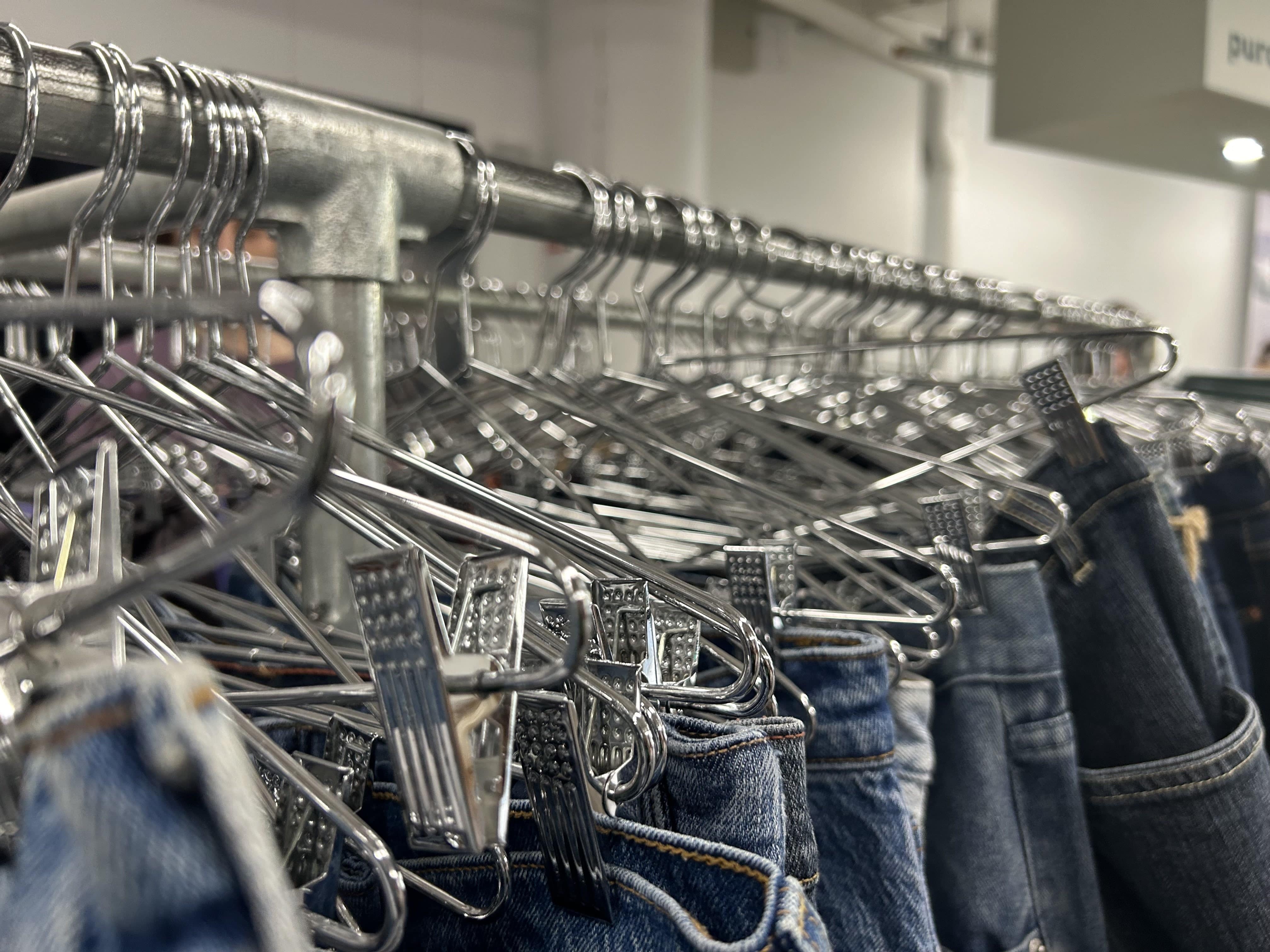 Close-up shot of a rack of jeans on hangers