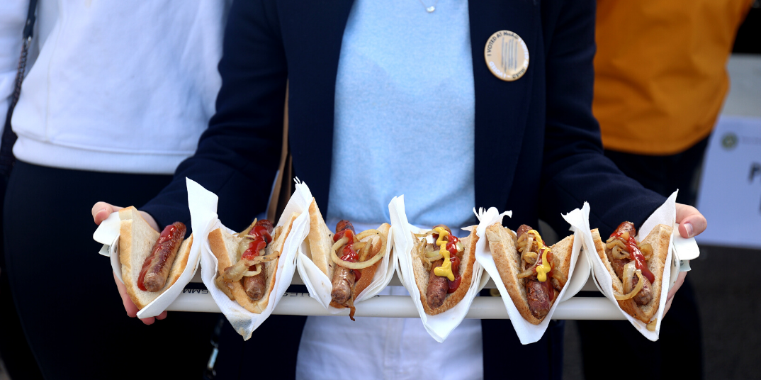 A line of democracy sausages being held by a person.