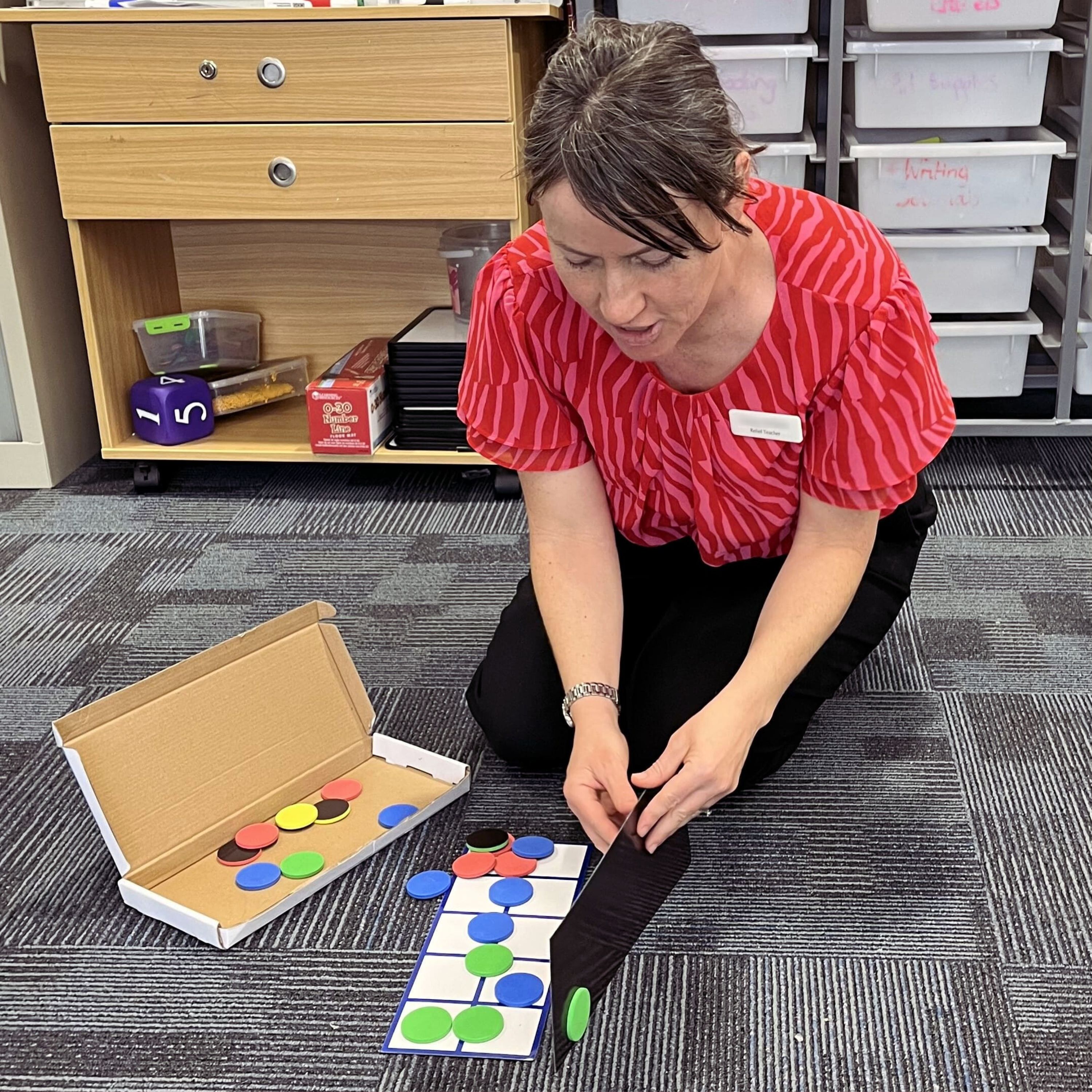 Laura kneeling on ground, setting up learning resource.