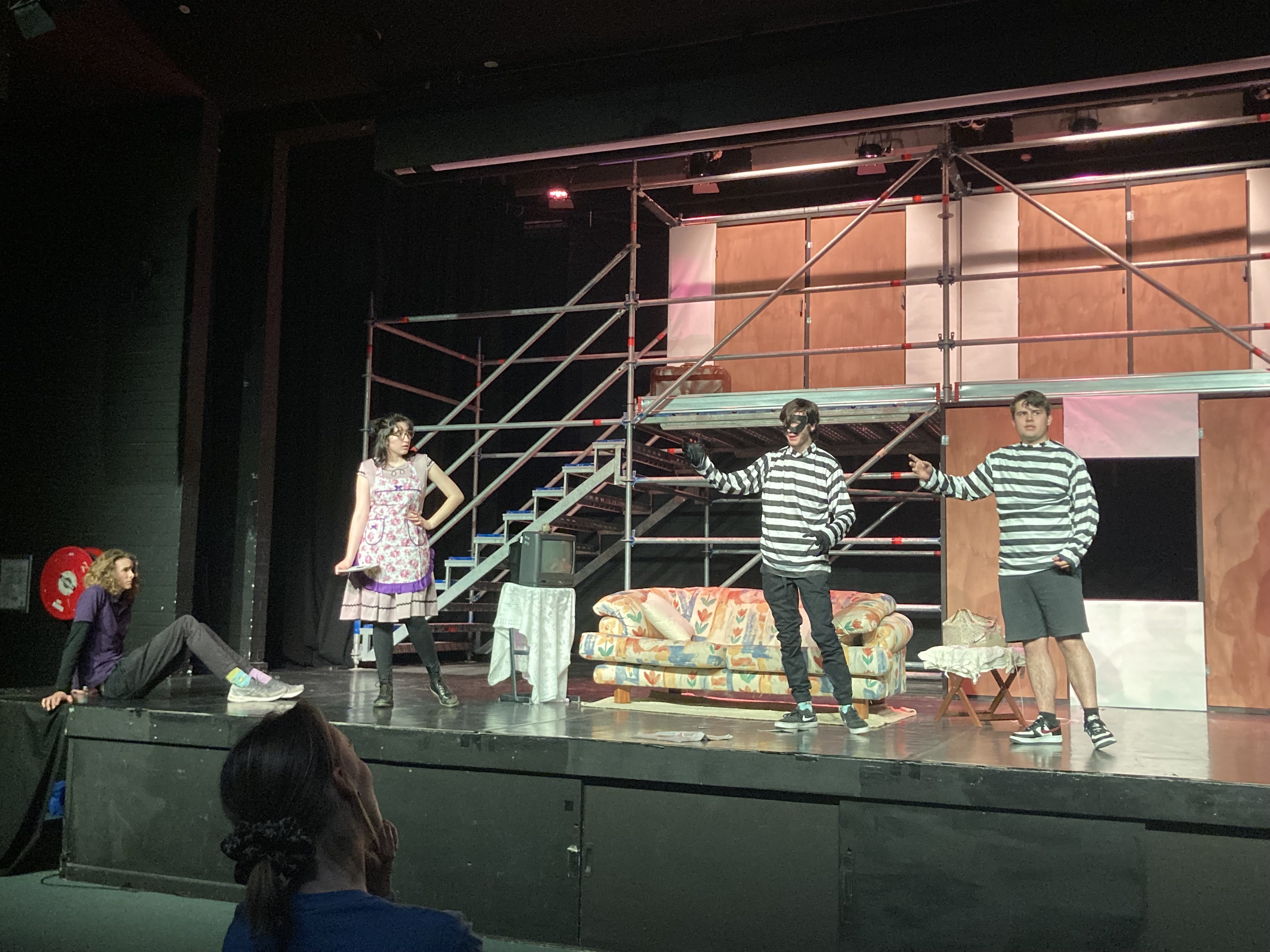 Four actors stand on stage, two are dressed as burglars