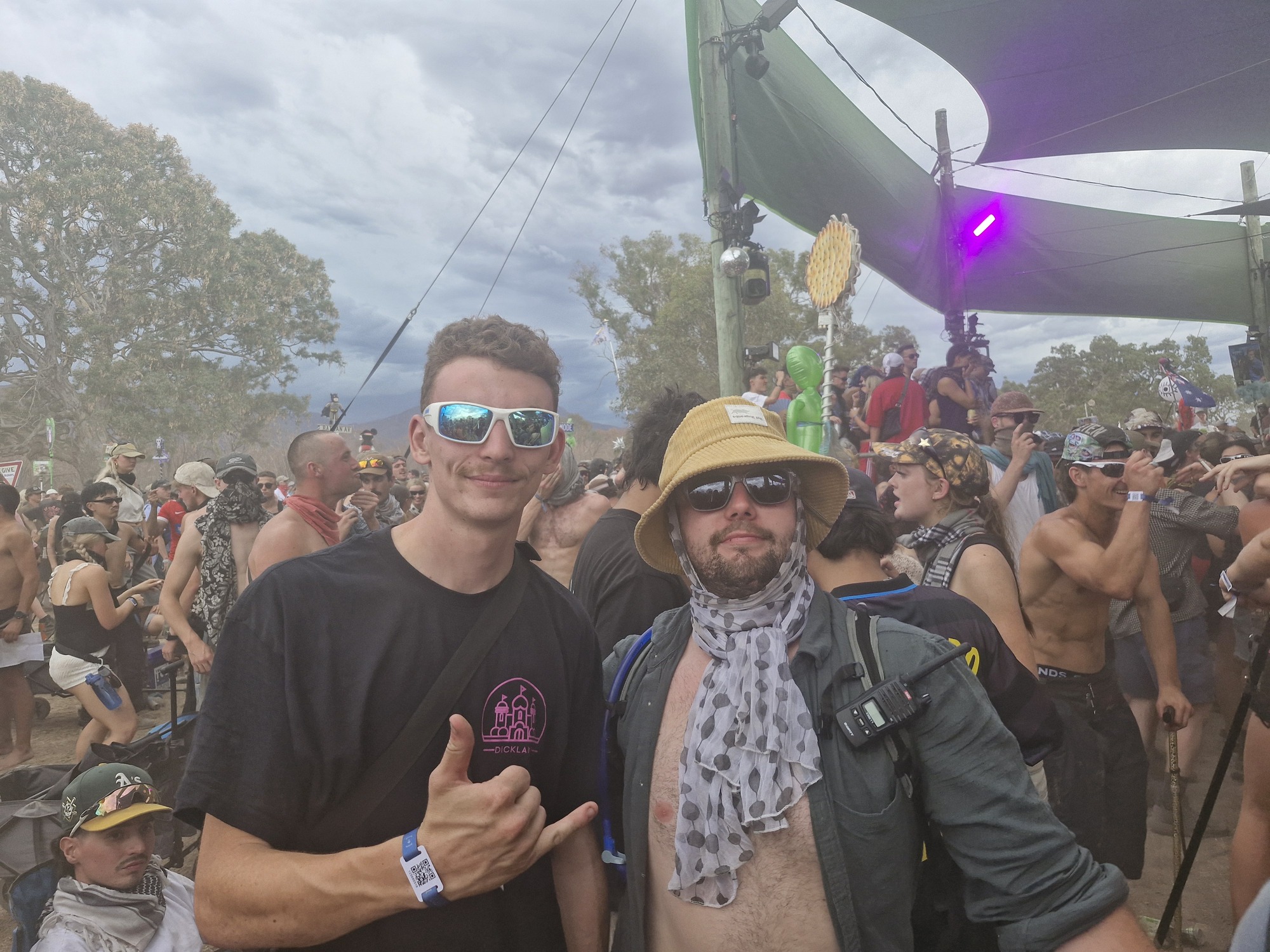 Two men standing in festival crowd smiling at camera