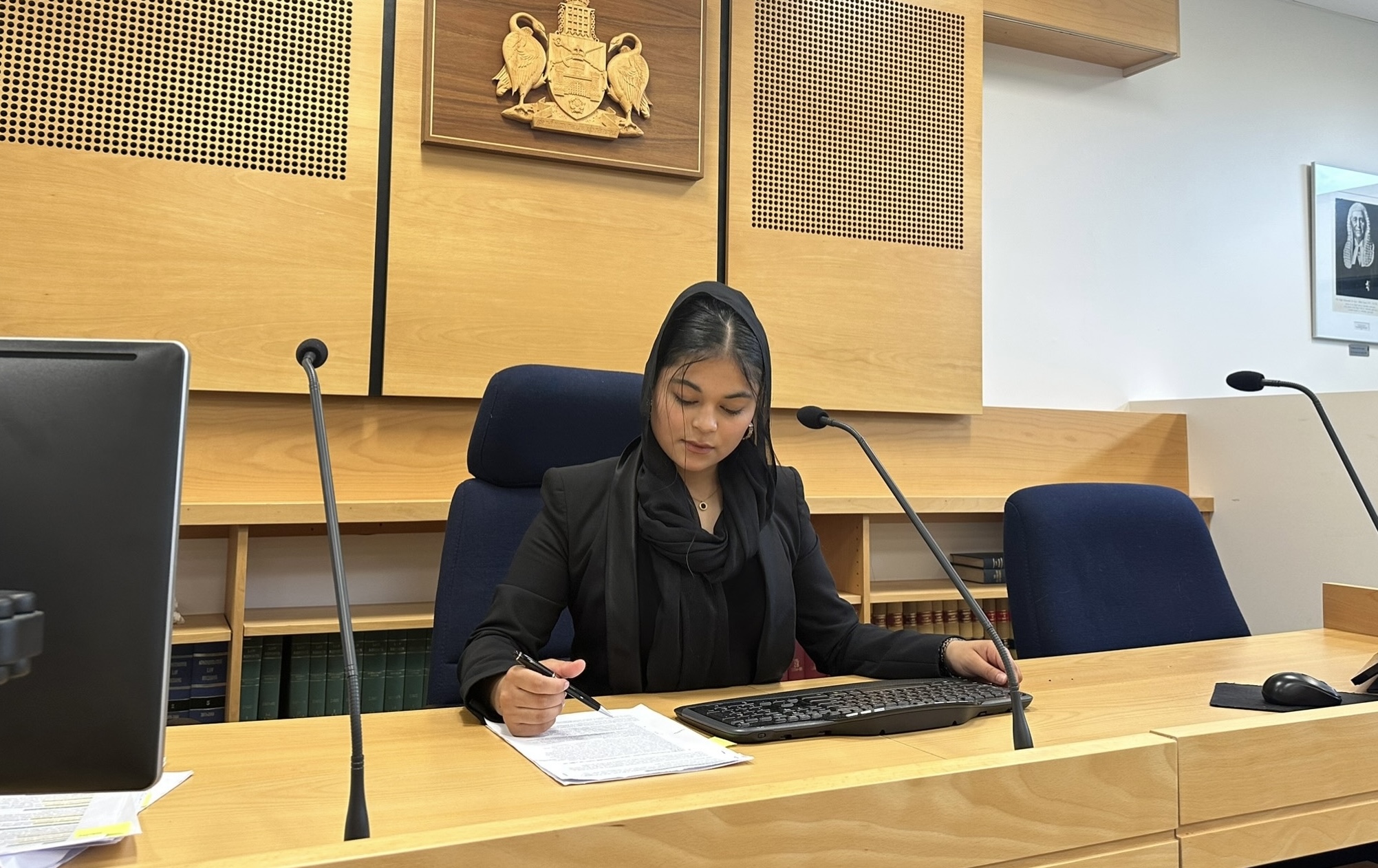 Frishta sitting at a judge’s desk in a courtroom.