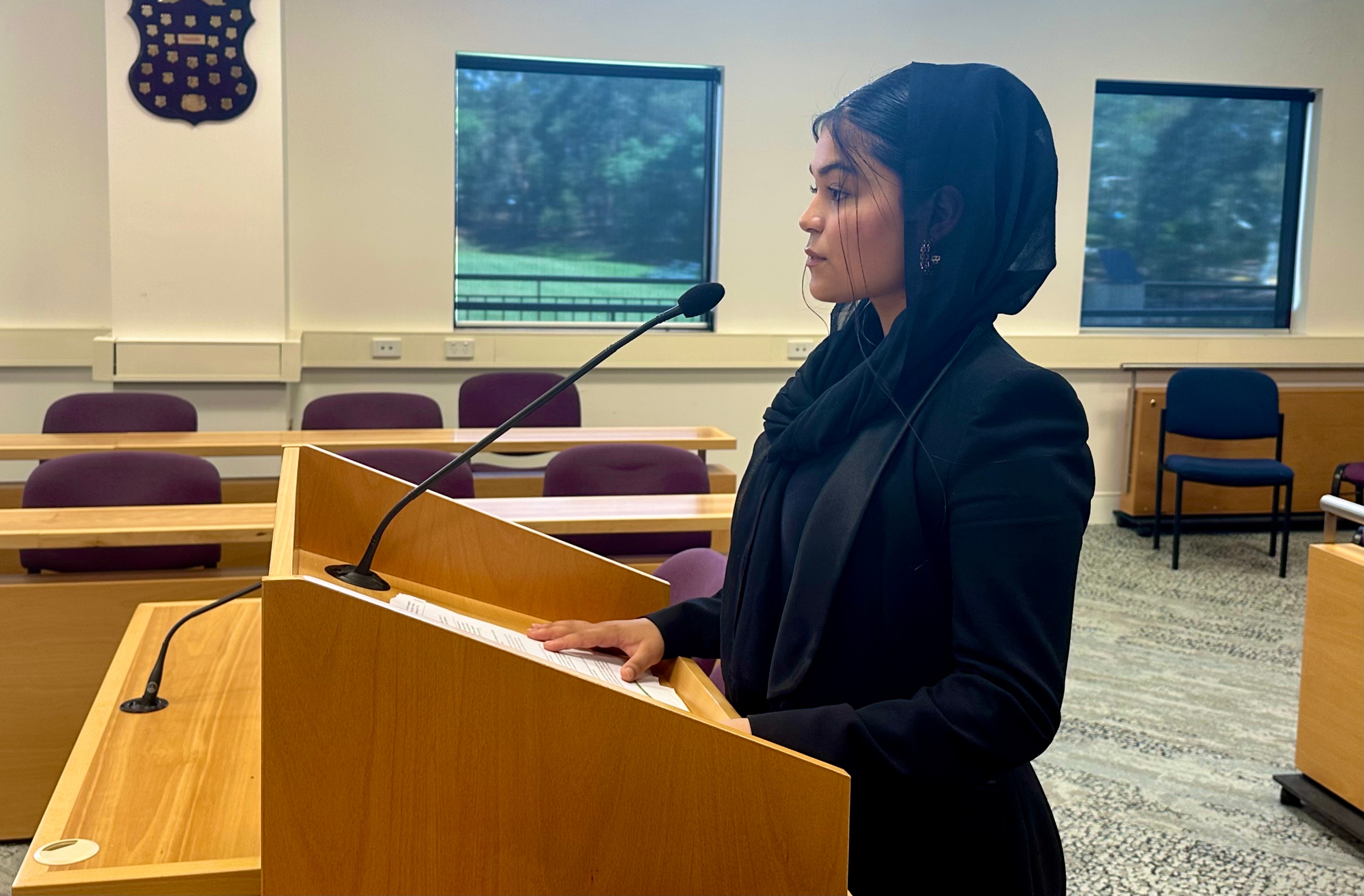 Frishta standing at a law court podium.