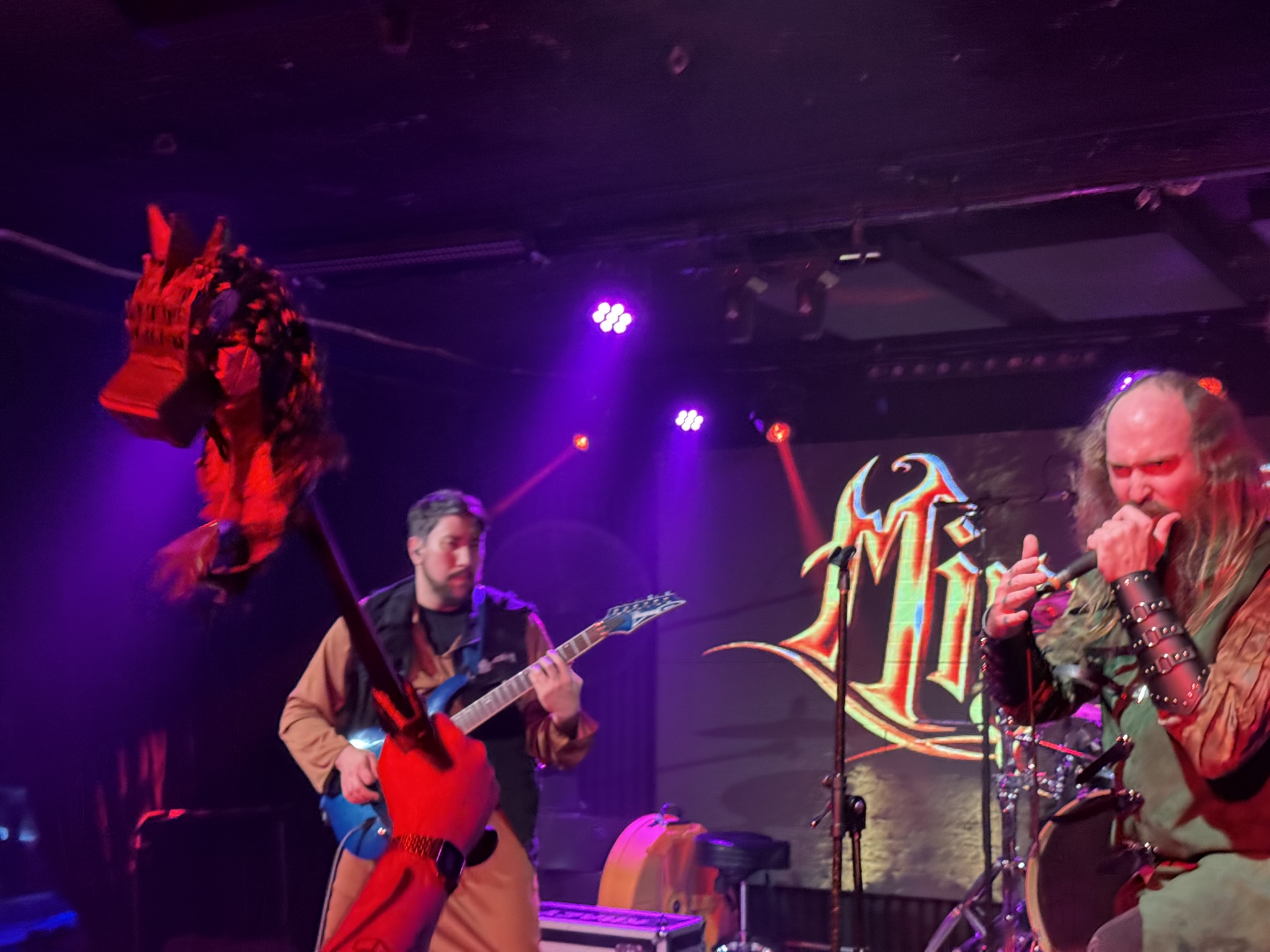Mirrorshield playing on stage with the head of a Pinata held on the end of a sword in the foreground