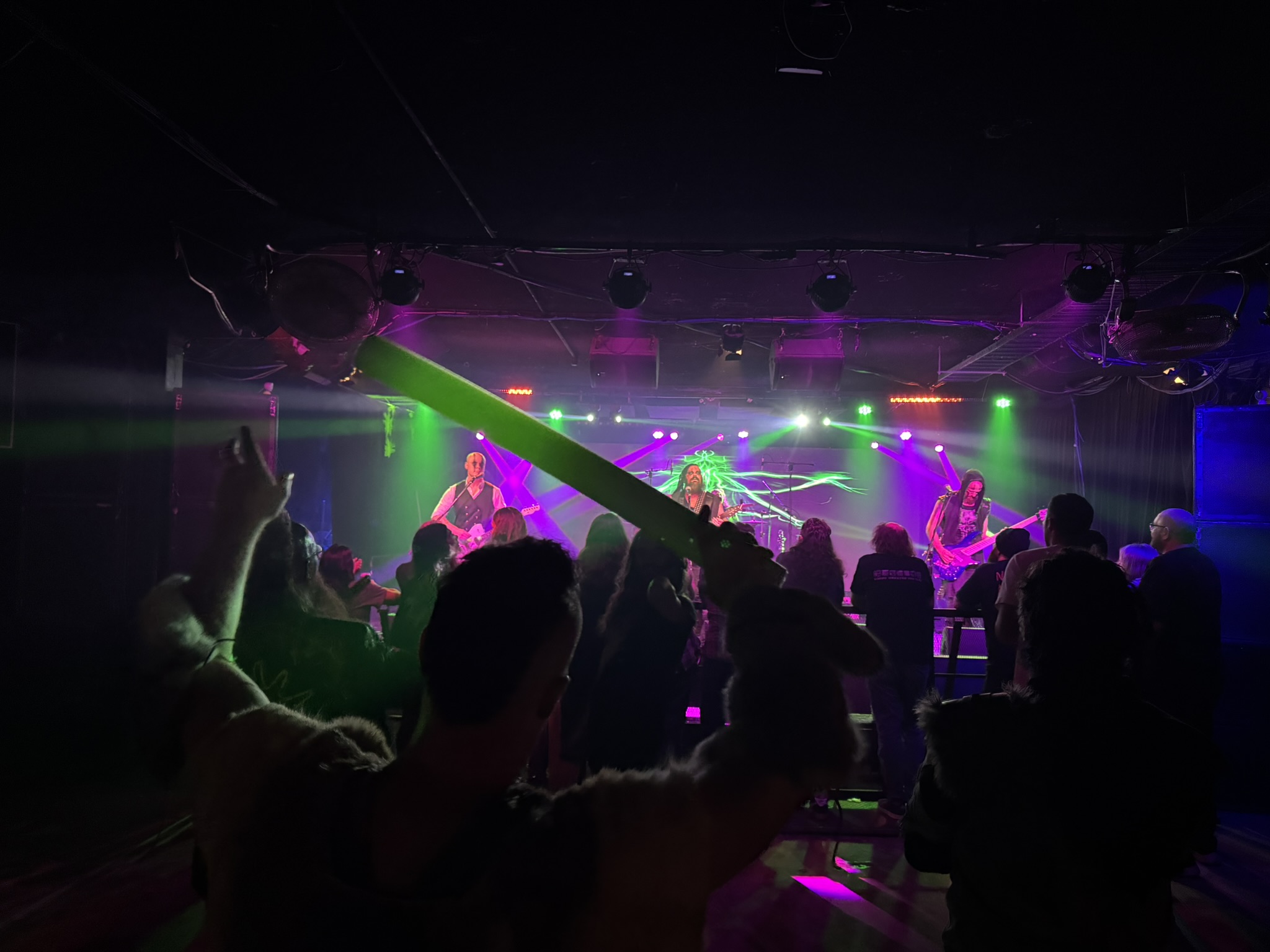 Pyrefly perform on stage while in the foreground the remaining audience is swaying along to the music, pool noodles in hand