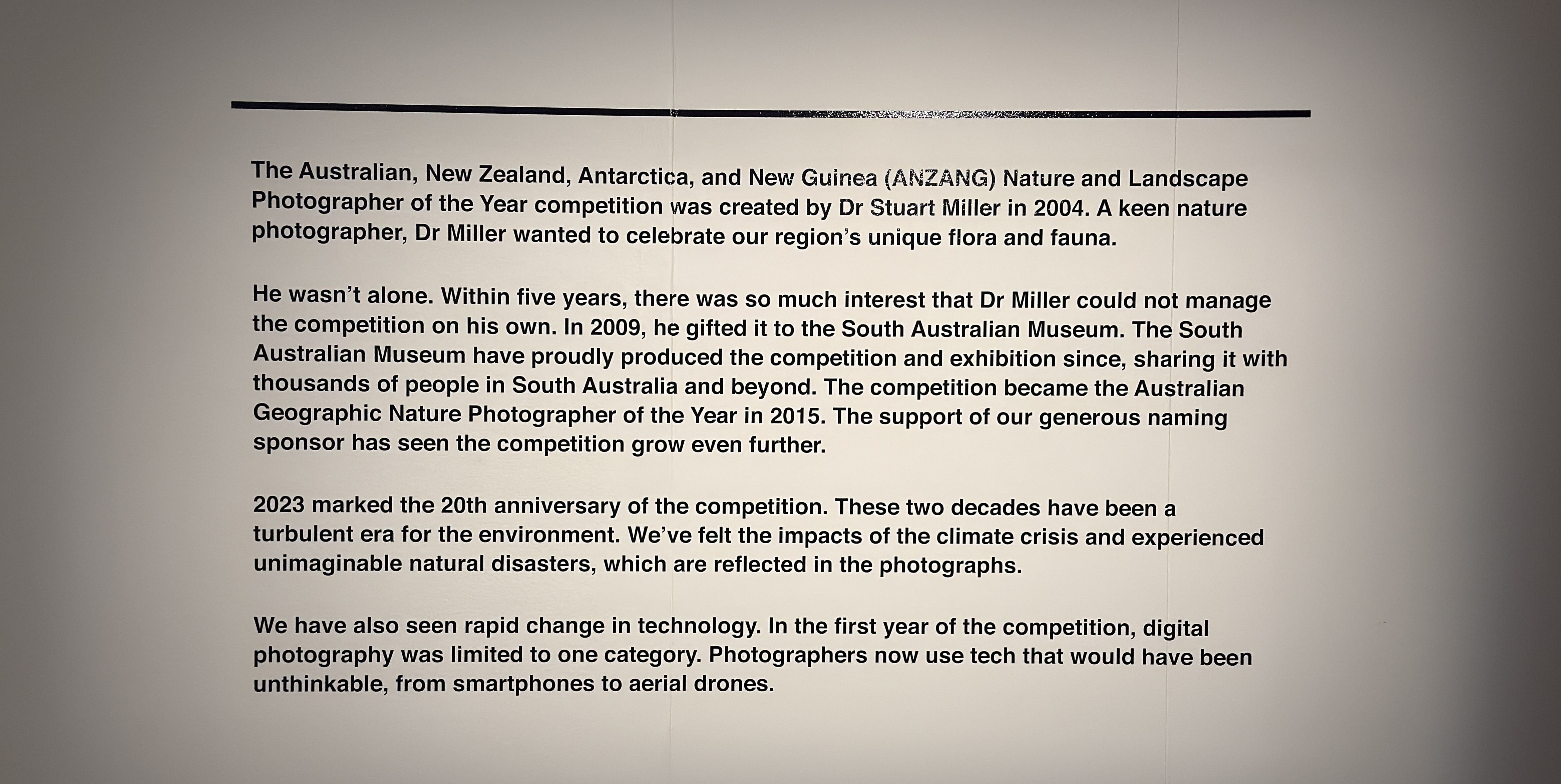 A white display panel at the entrance featuring text about the history of the exhibition.
