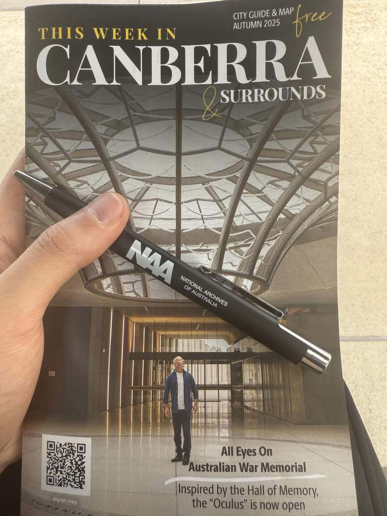 A guidebook titled 'This Week Surrounding Canberra' held by the writer.