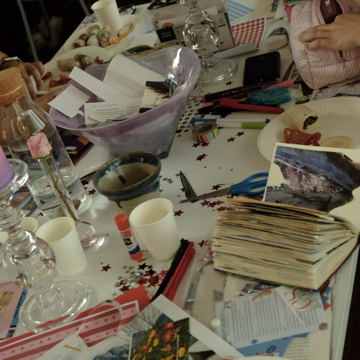 A table with collaging materials and open journals