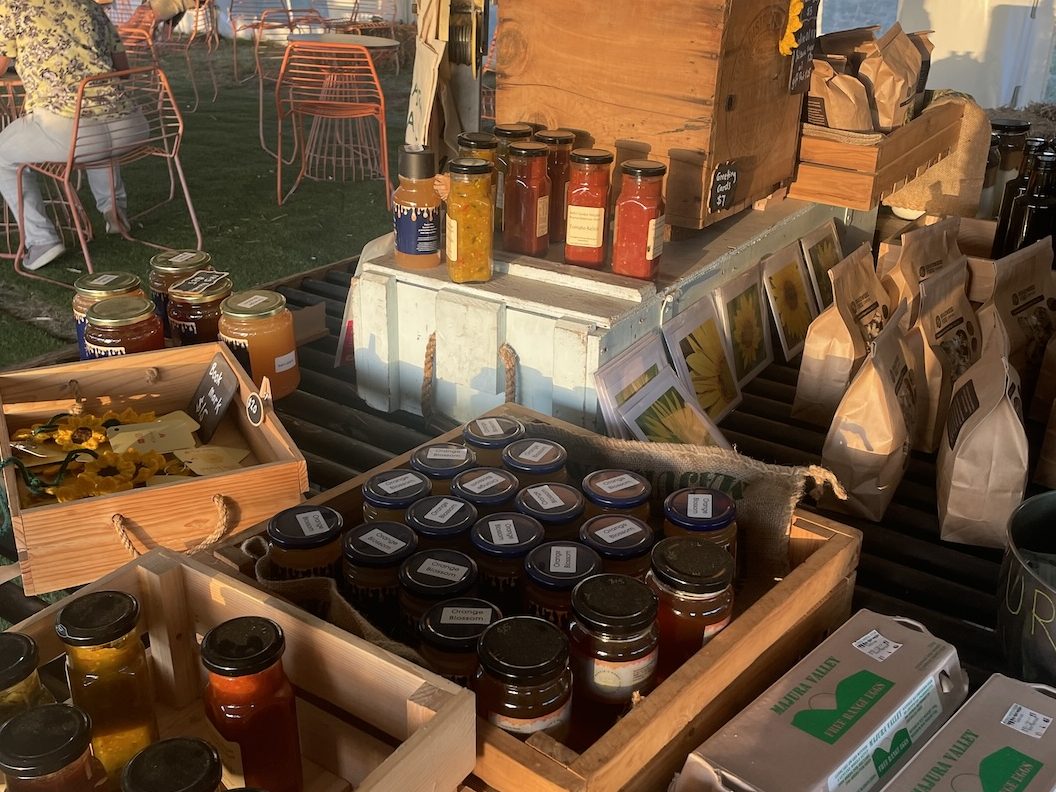 A display of local farm products including jars of honey, sauces, and various packaged goods on a farm table
