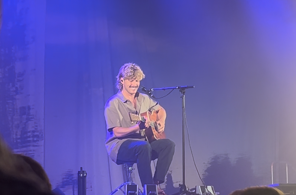 Ziggy Alberts, the headline act, smiling while singing and playing guitar.