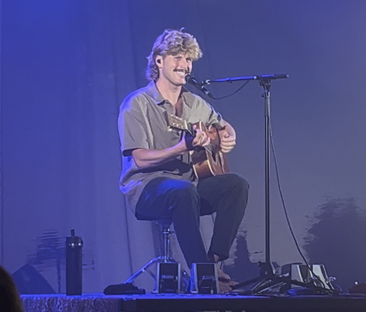 Ziggy Alberts smiling while playing guitar and singing
