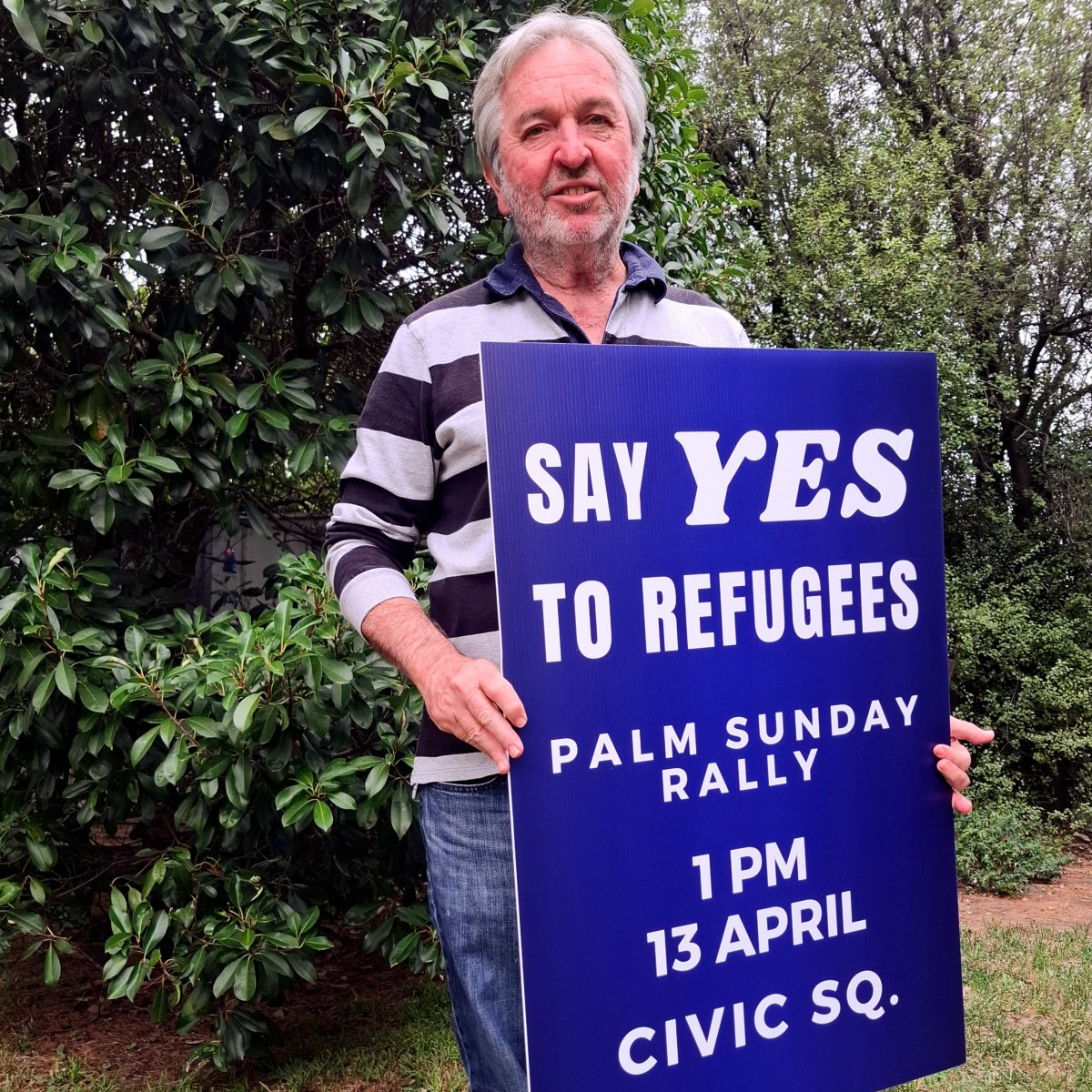 Prof. John Minns hold a say yes to refugee sign