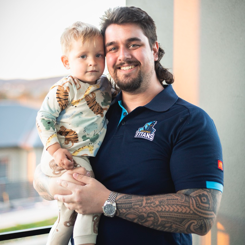 Clarkey posing for a picture with his son in his arms.