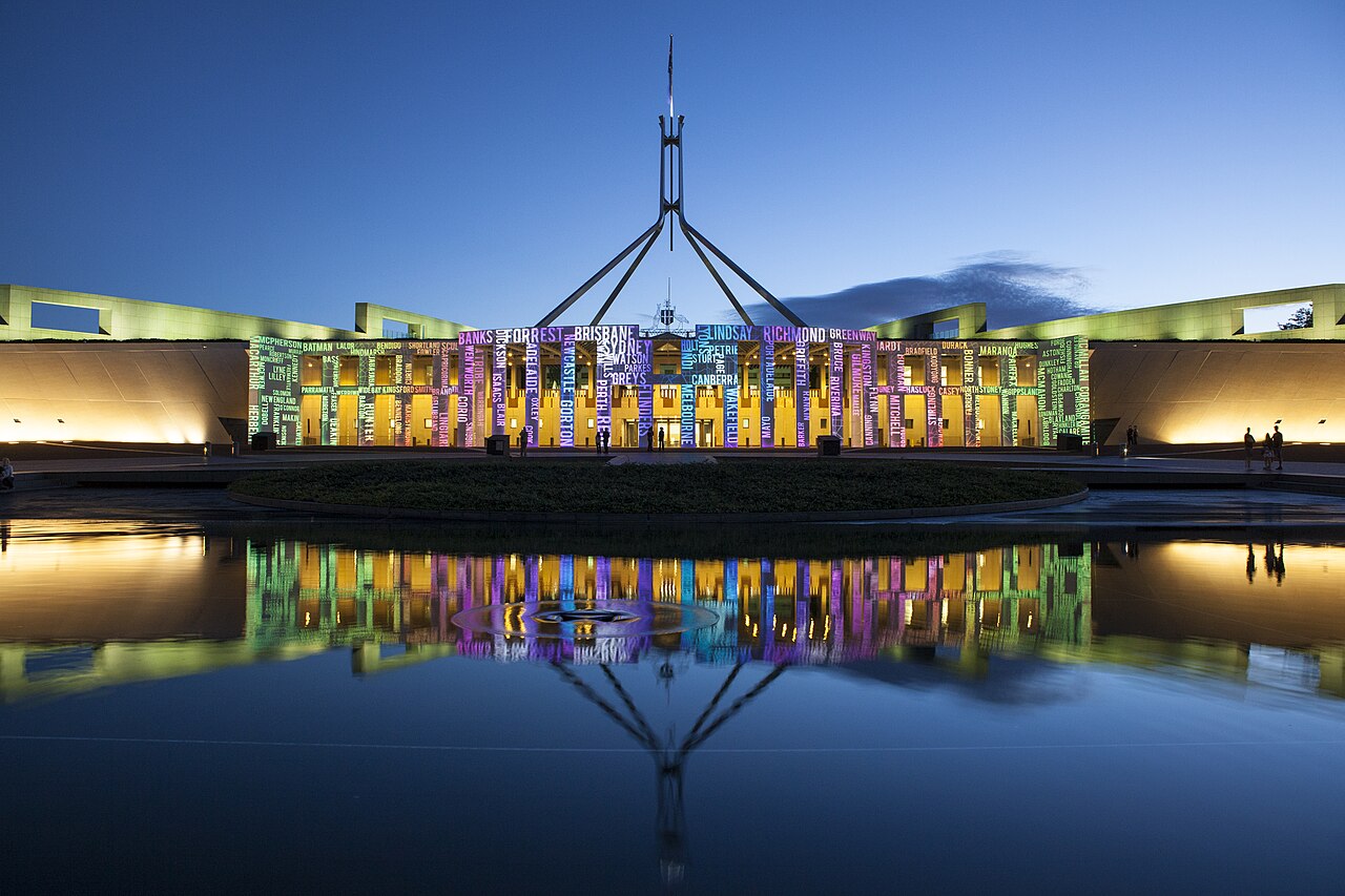 A photograph of Parliament house lit up at dusk