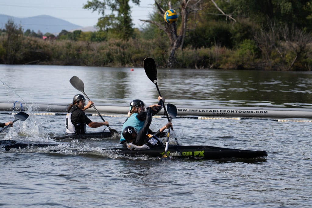 Two People wearing protective face masks both paddling hard in kayaks.