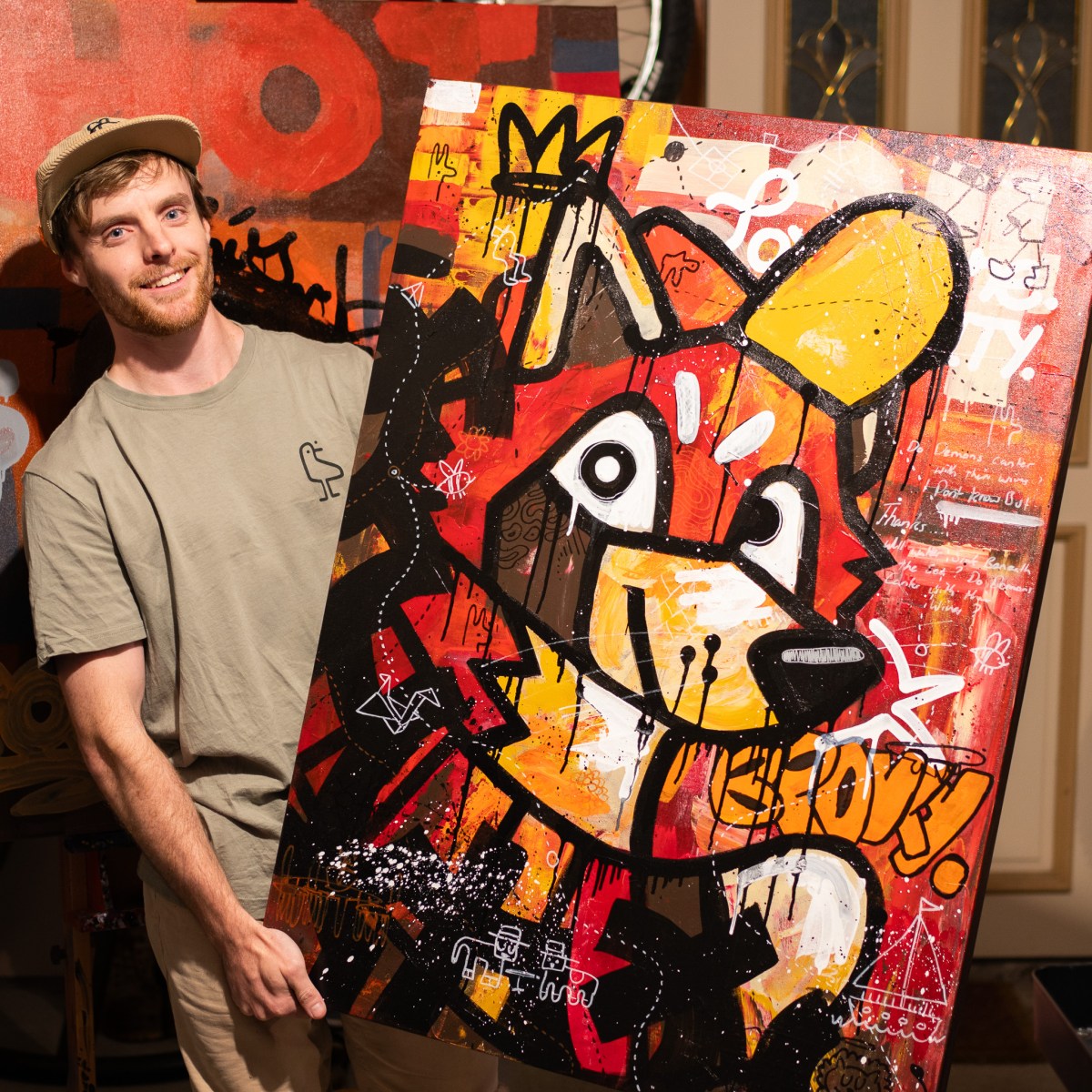 Sweigz holding up a canvas with one of his animal paintings