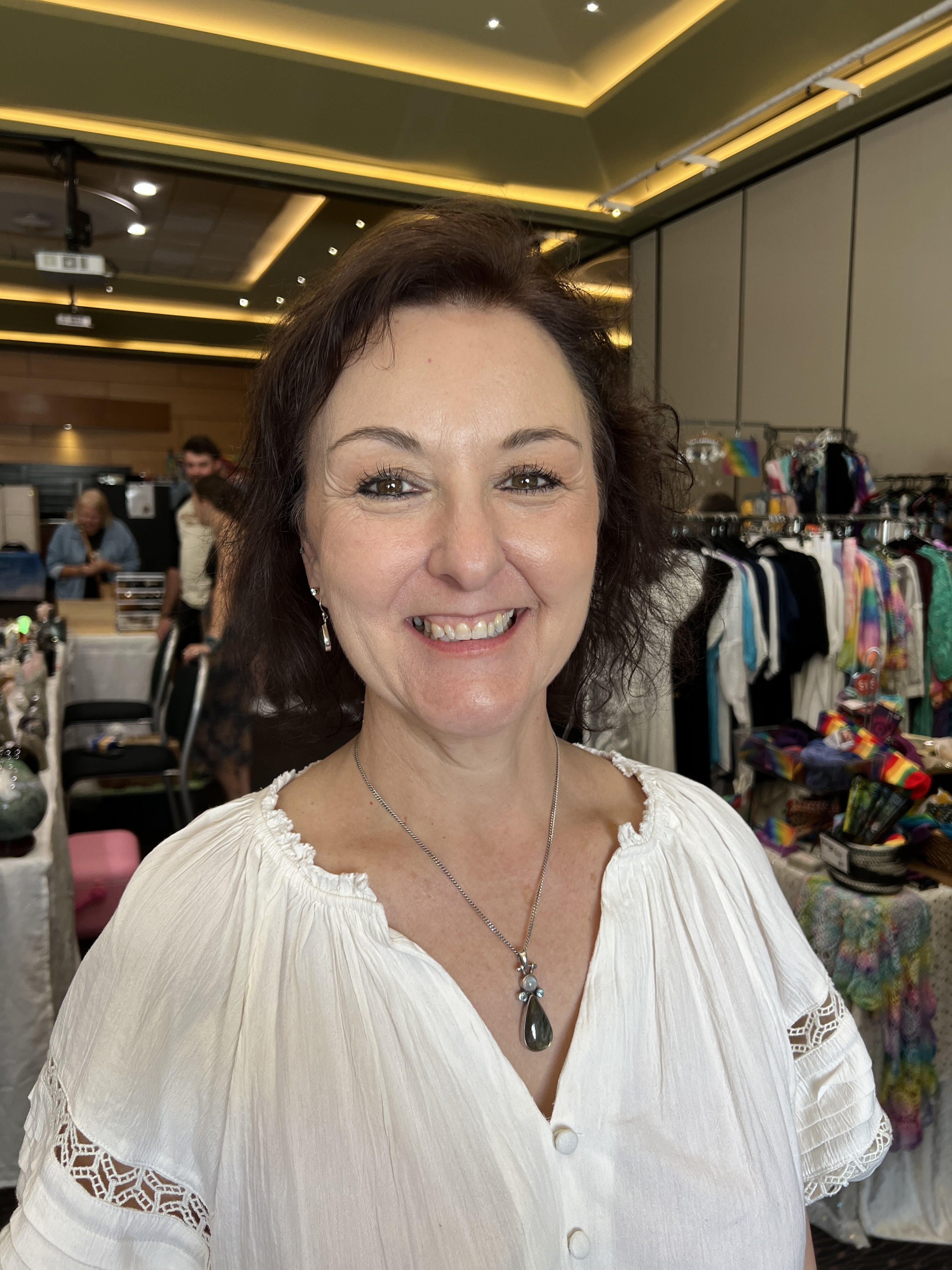 Woman with brown hair and brown eyes smiling and wearing a white shirt