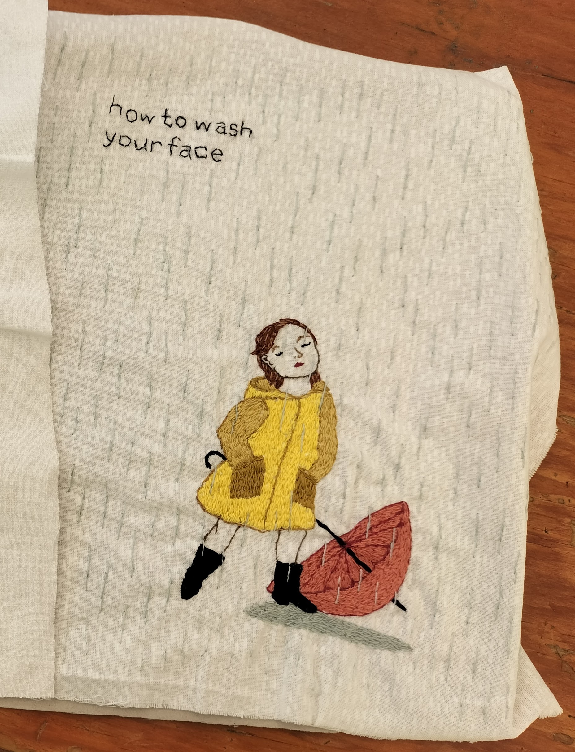 Panel with children's book embroidery of girl washing her face in the rain, created by Vicky.
