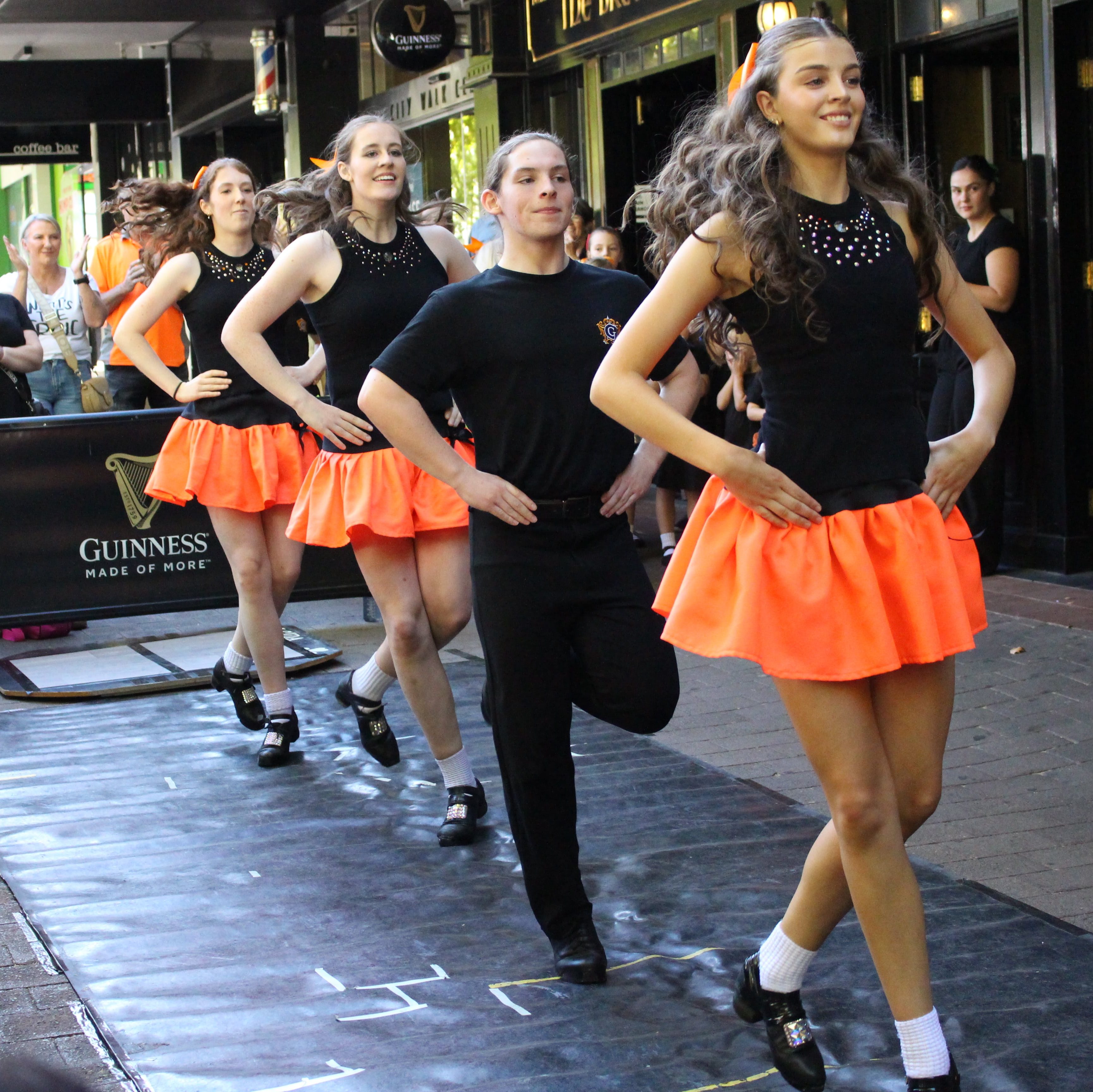 Four Irish dancers with their hands on their hips performing the outside crowd.